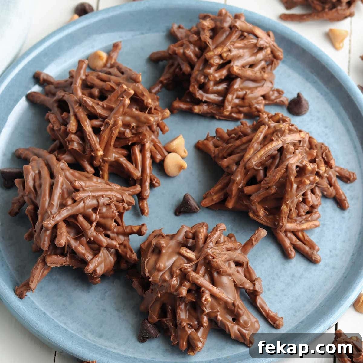Quick No-Bake Haystack Cookies Recipe 2 No bake chocolate peanut butter haystack cookies with chow mein noodles on a blue plate.