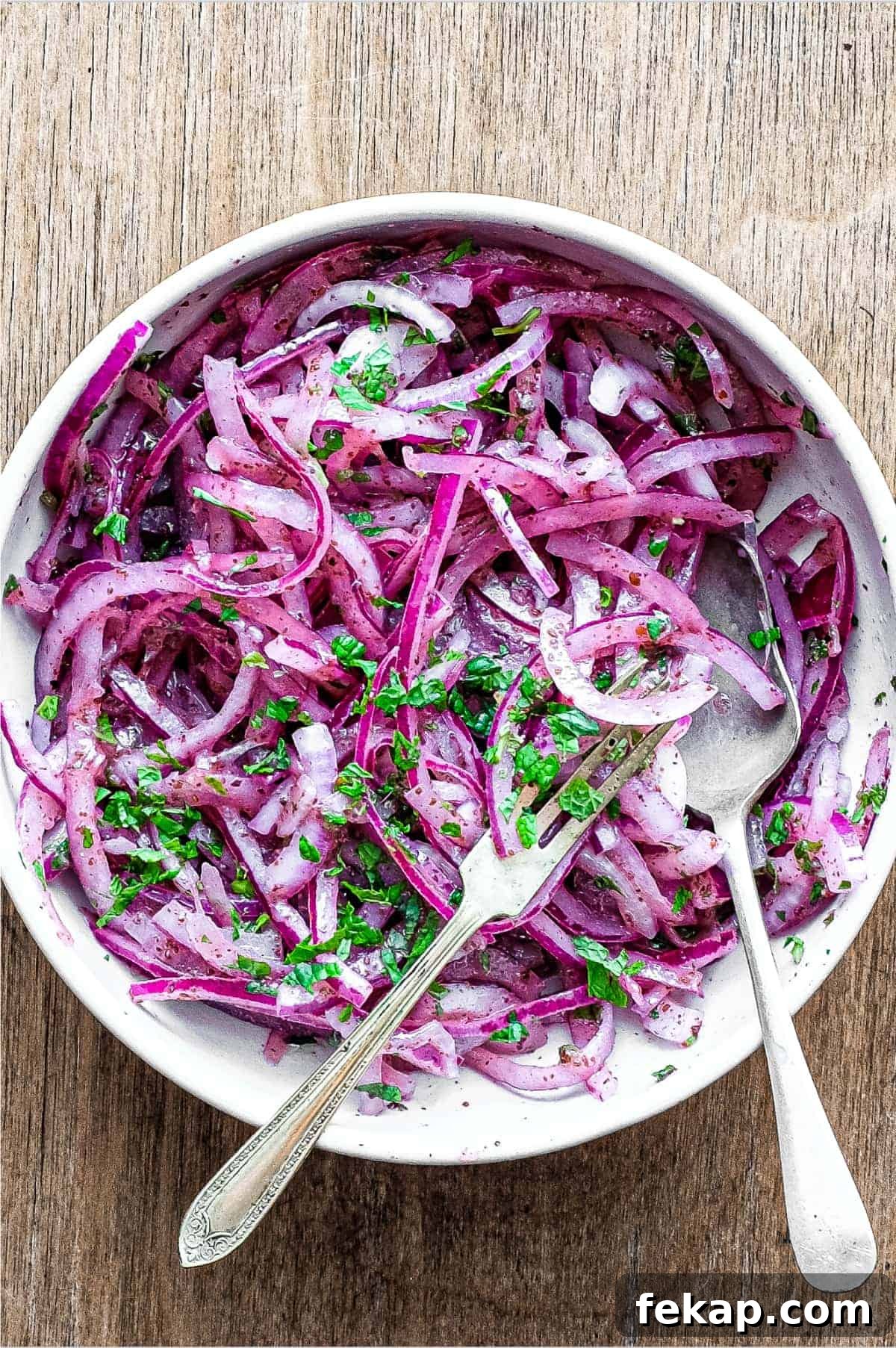 Sumac Onions | cookeatworld.com A small bowl of Sumac Onions with a small serving fork and spoon