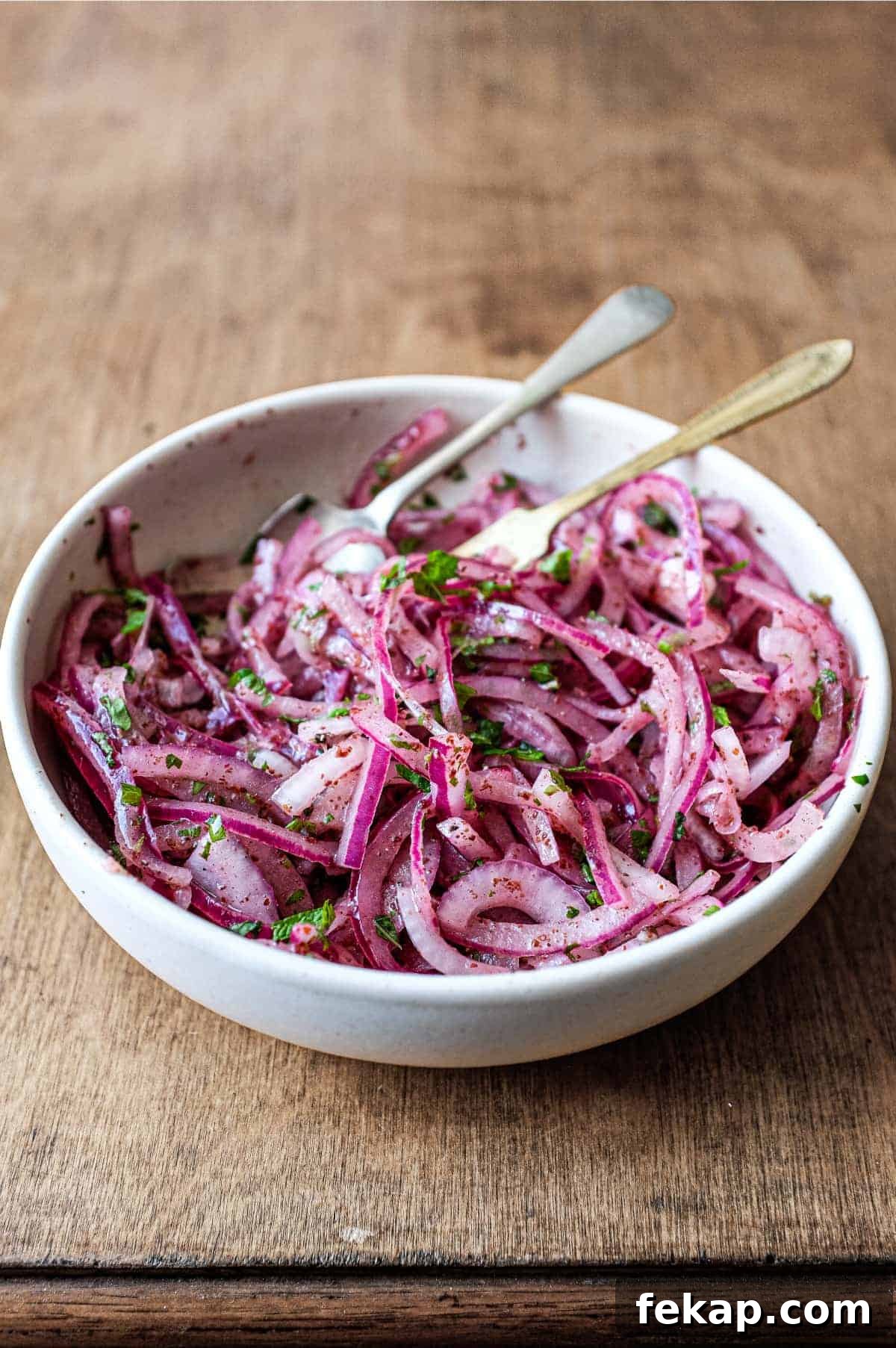 Sumac Onions | cookeatworld.com A small bowl of Sumac Onions with a small serving fork and spoon