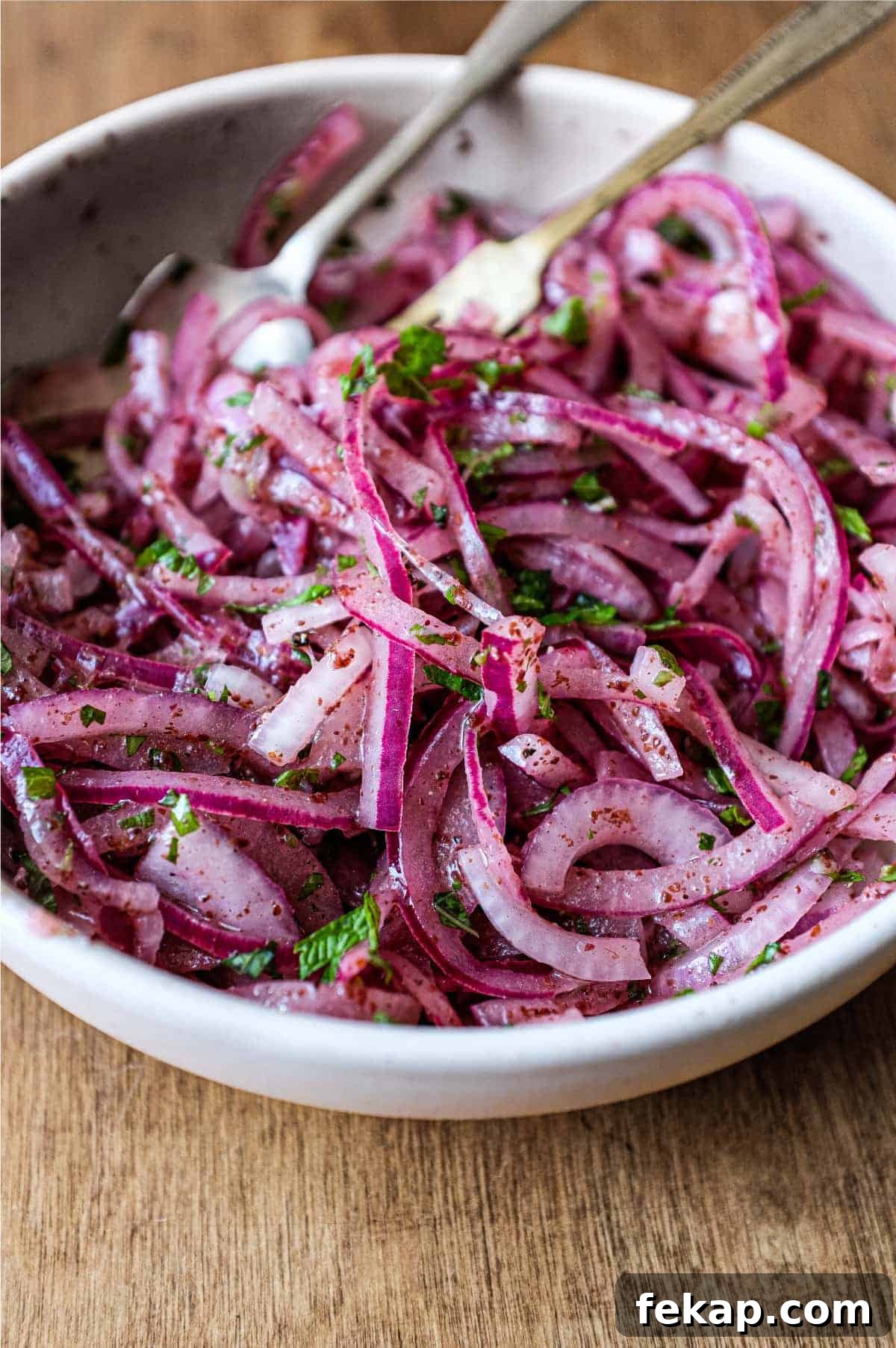 Sumac Onions | cookeatworld.com A small bowl of Sumac Onions with a small serving fork and spoon