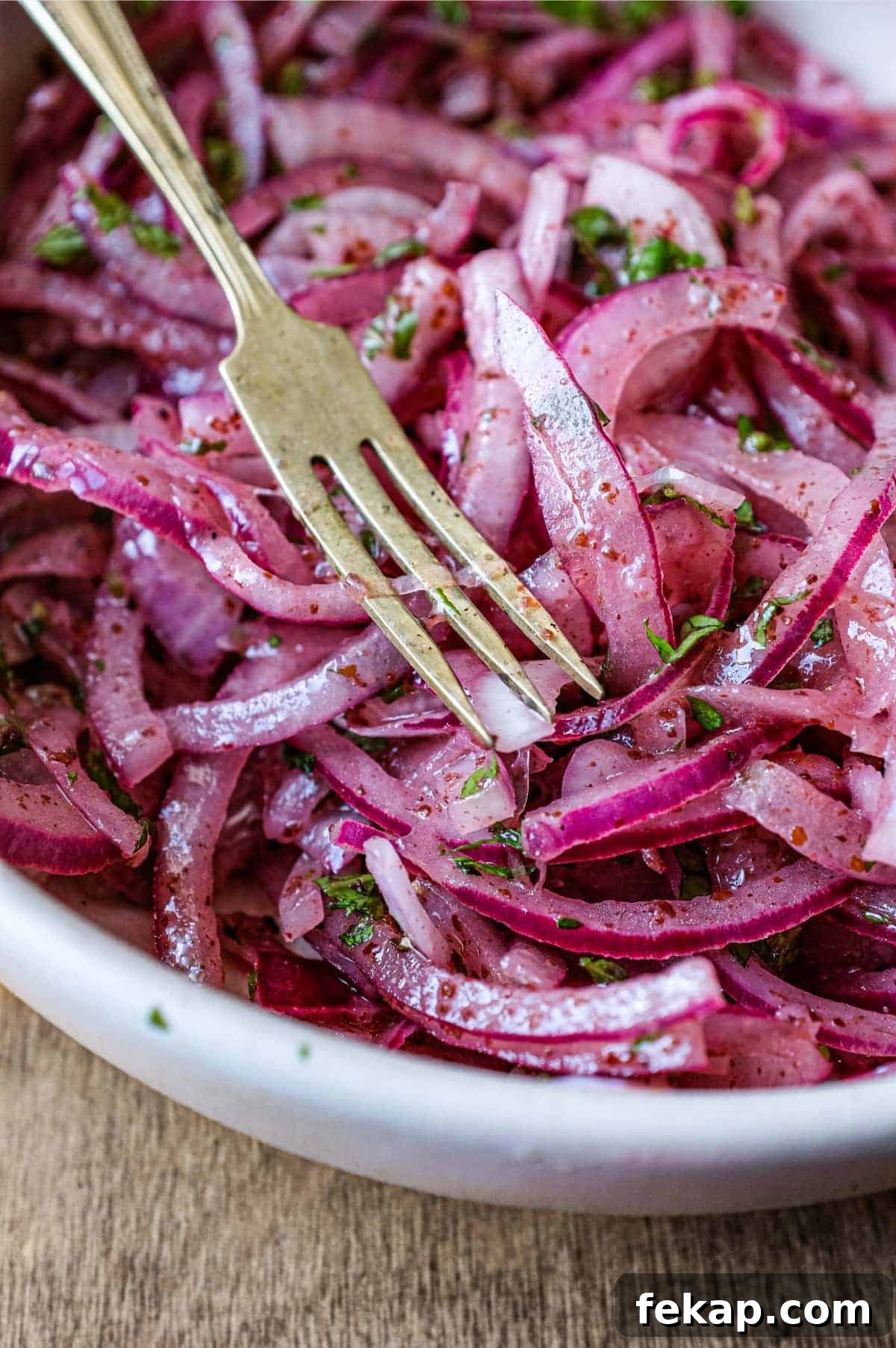 Sumac Onions | cookeatworld.com A small bowl of Sumac Onions with a small serving fork and spoon