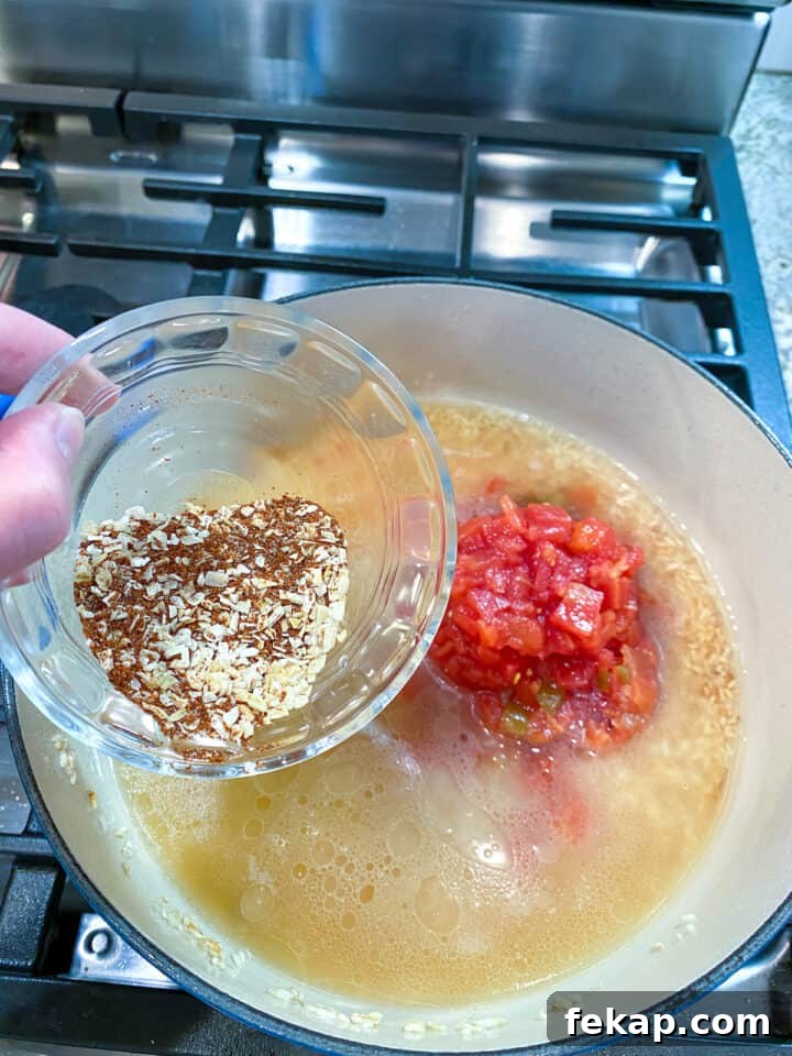 Restaurant-Style Mexican Fried Rice Recipe 13 A small dish of spices held over a pan with broth, canned tomatoes and rice.