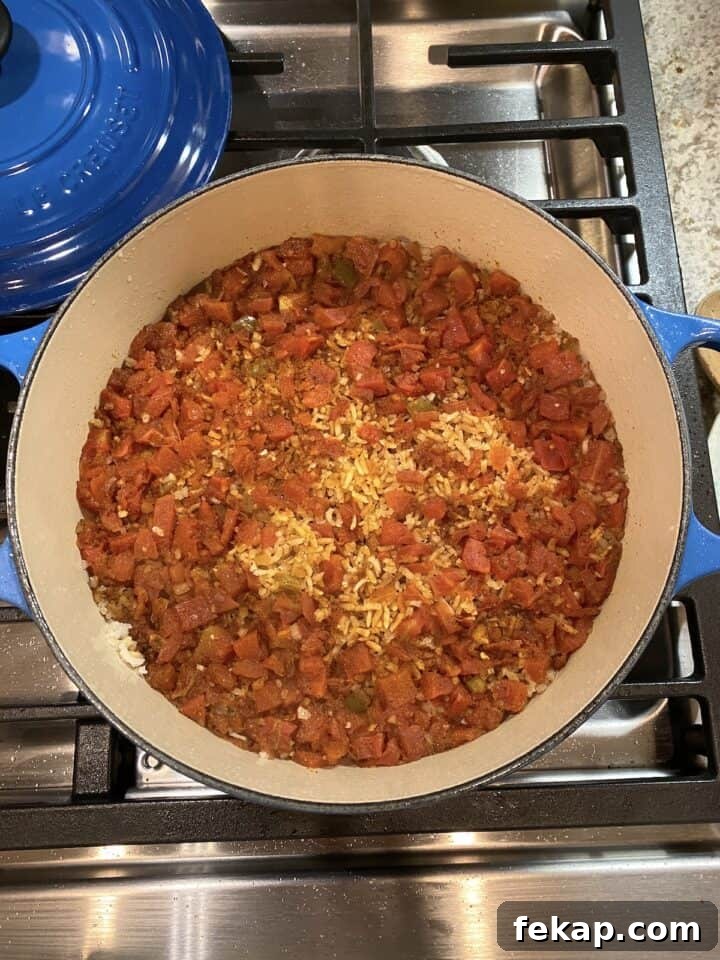 Restaurant-Style Mexican Fried Rice Recipe 14 A pot of cooked rice with tomatoes on top of the rice.