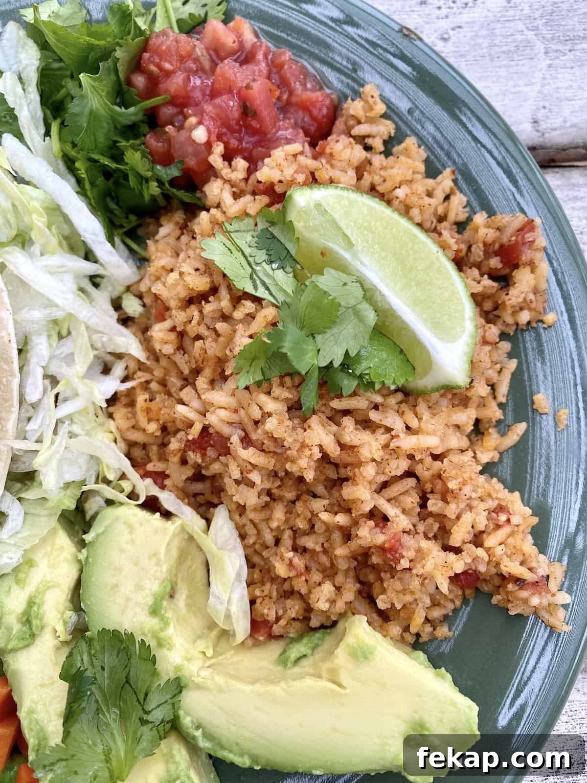 Restaurant-Style Mexican Fried Rice Recipe 17 Mexican rice on a plate with avocado on the side, topped with lime.