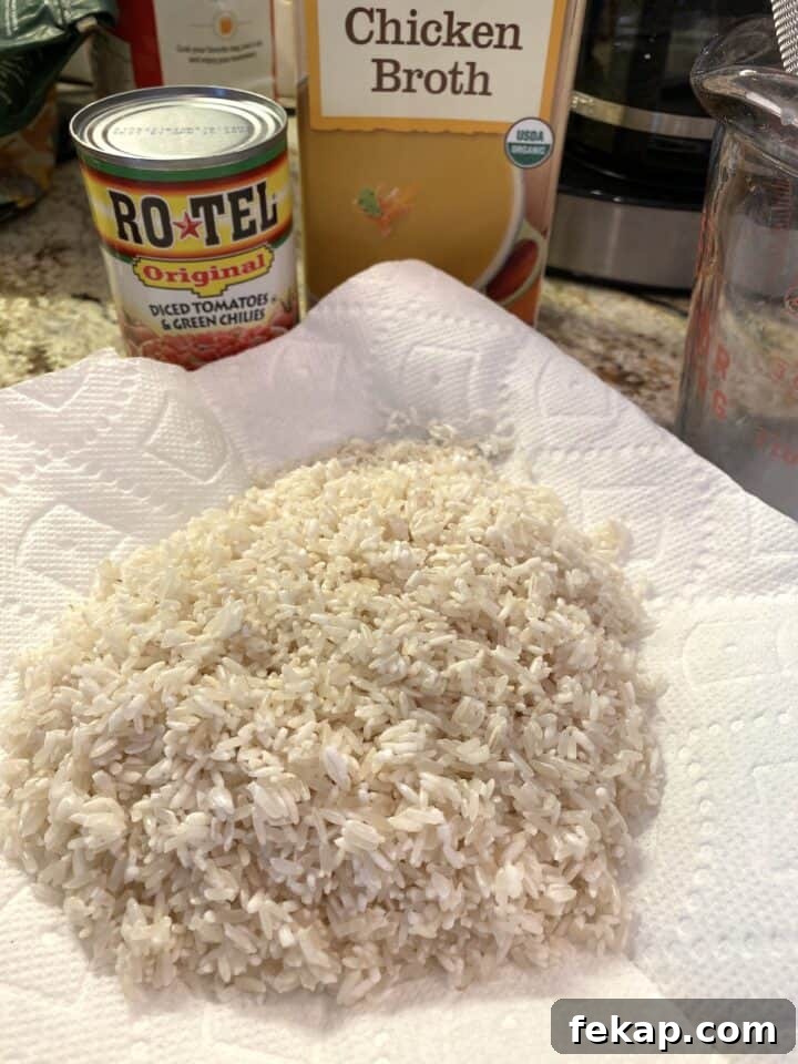 Restaurant-Style Mexican Fried Rice Recipe 9 Rice drying a paper towel with canned tomatoes and boxed chicken broth in the background.