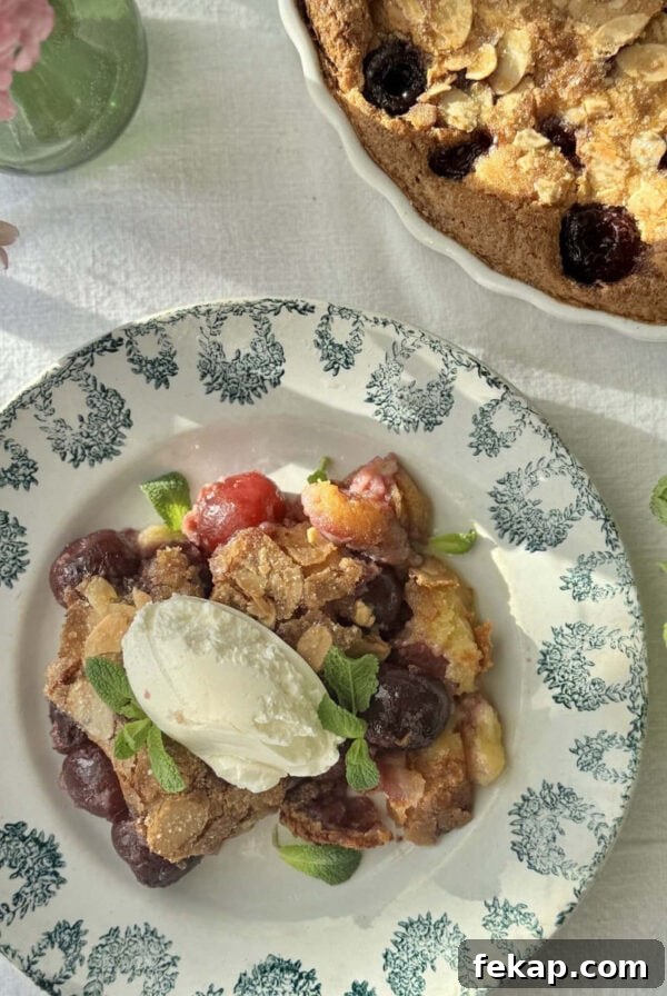 clafoutis aux cerises in a bowl with mascarpone on top and more fresh cherries.