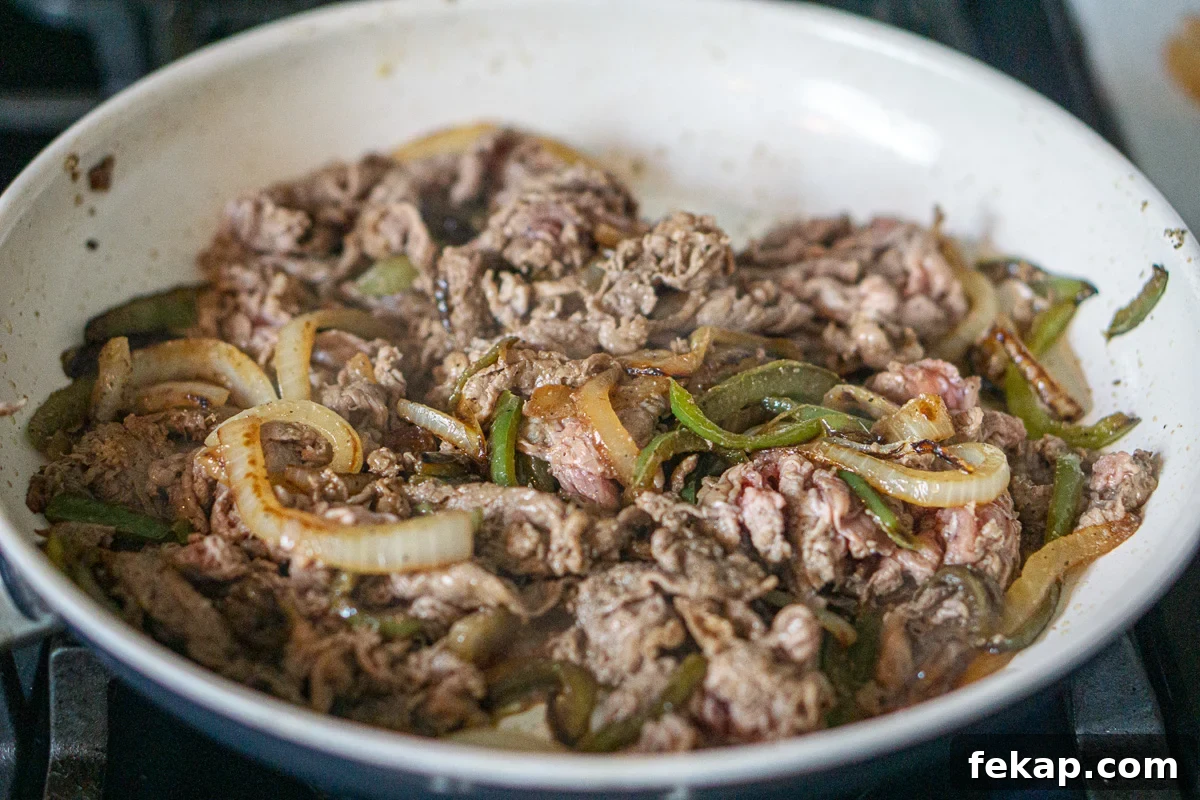Philly Cheesesteak Sliders on Hawaiian Rolls Game Day Recipe 5 Shaved steak is added to the onion and pepper mixture.