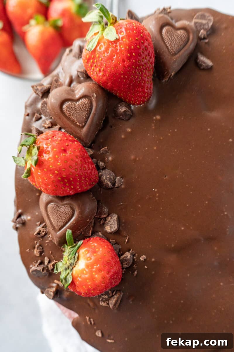 Moist Chocolate Strawberry Cake Recipe 3 top of valentine cake with strawberries, heart candies, and crushed chocolate on top of ganache.