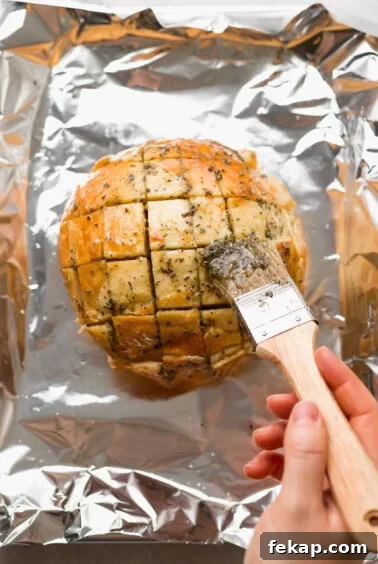 a person using a knife to cut a loaf of bread.