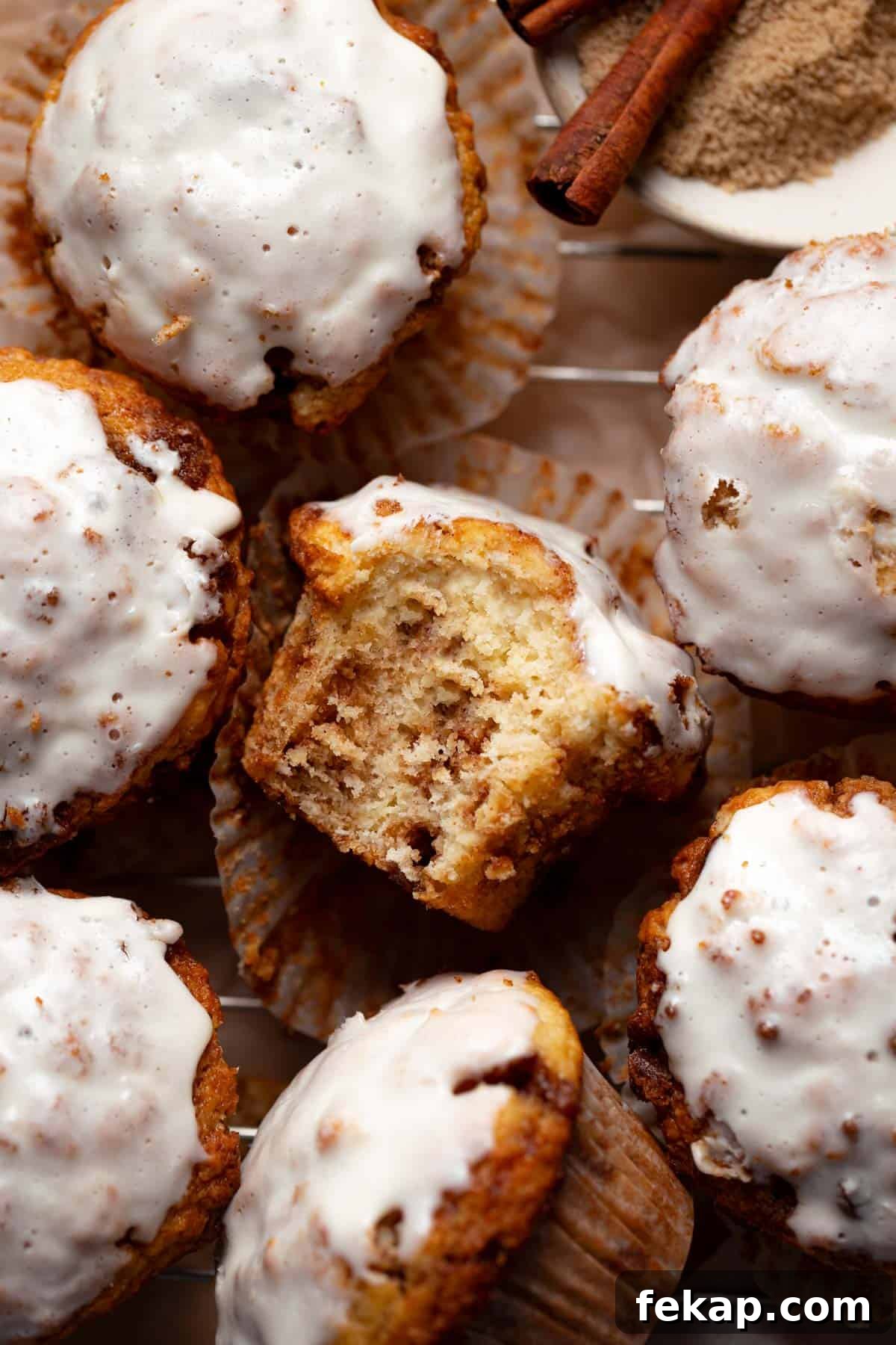 Fluffy Cinnamon Roll Muffins with Cream Cheese Icing Recipe 2 A cinnamon roll muffin with a bite taken out showing cinnamon sugar swirls inside.