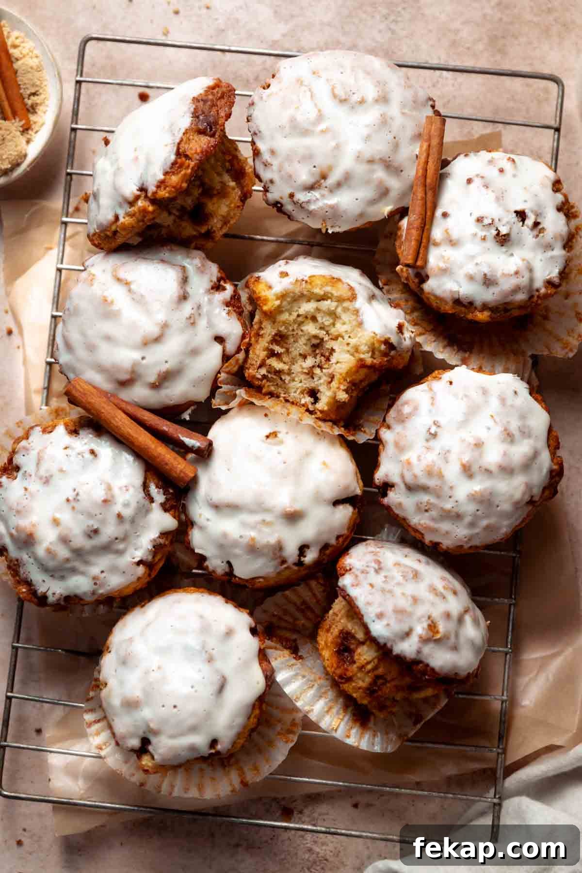 Fluffy Cinnamon Roll Muffins with Cream Cheese Icing Recipe 7 Cinnamon bun muffins covered in cream cheese icing on a wire cooling rack.