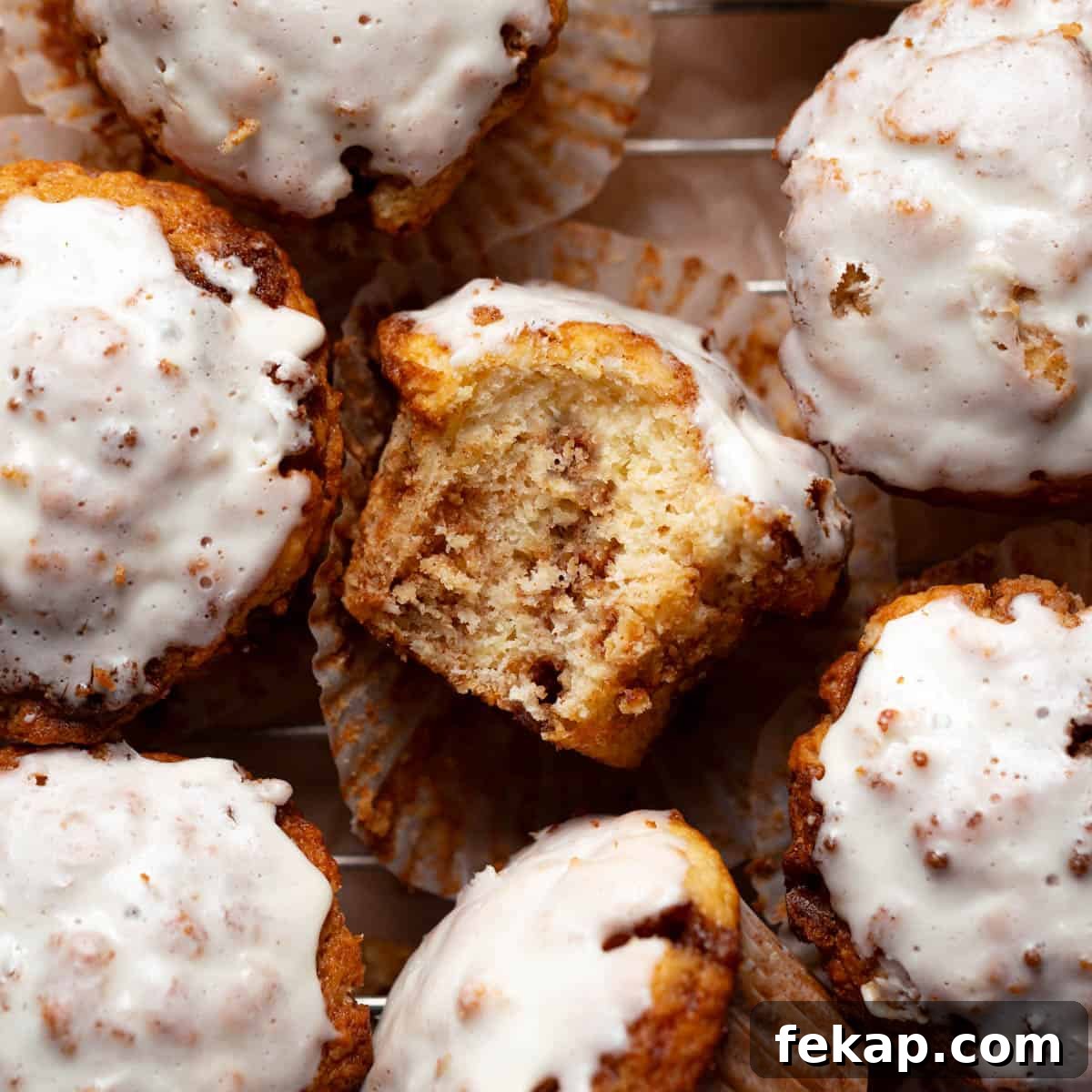 Fluffy Cinnamon Roll Muffins with Cream Cheese Icing Recipe 8 Cinnamon roll muffin with a bite taken out of it on a wire cooling rack.