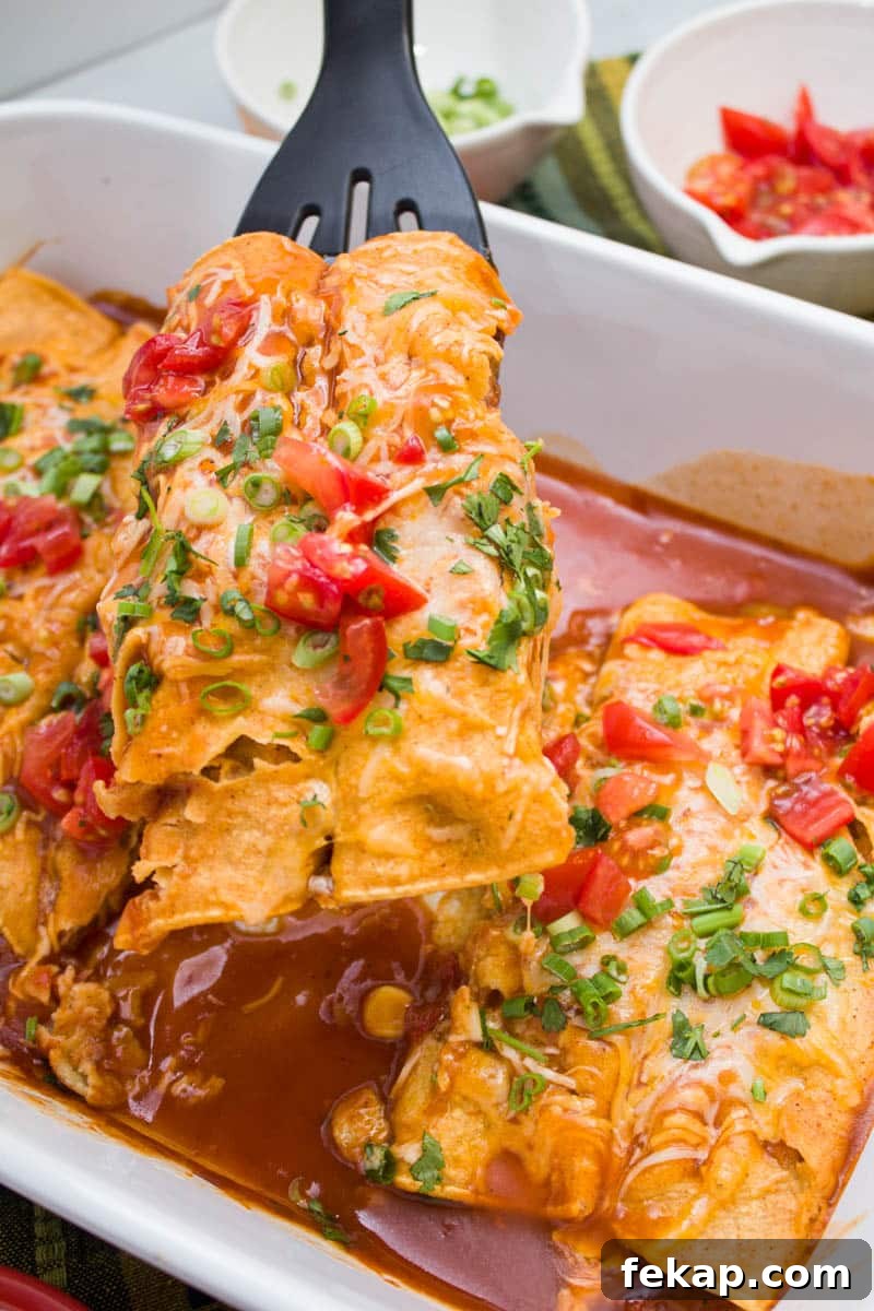 Lifting chicken enchiladas out of a baking dish with a spatula.