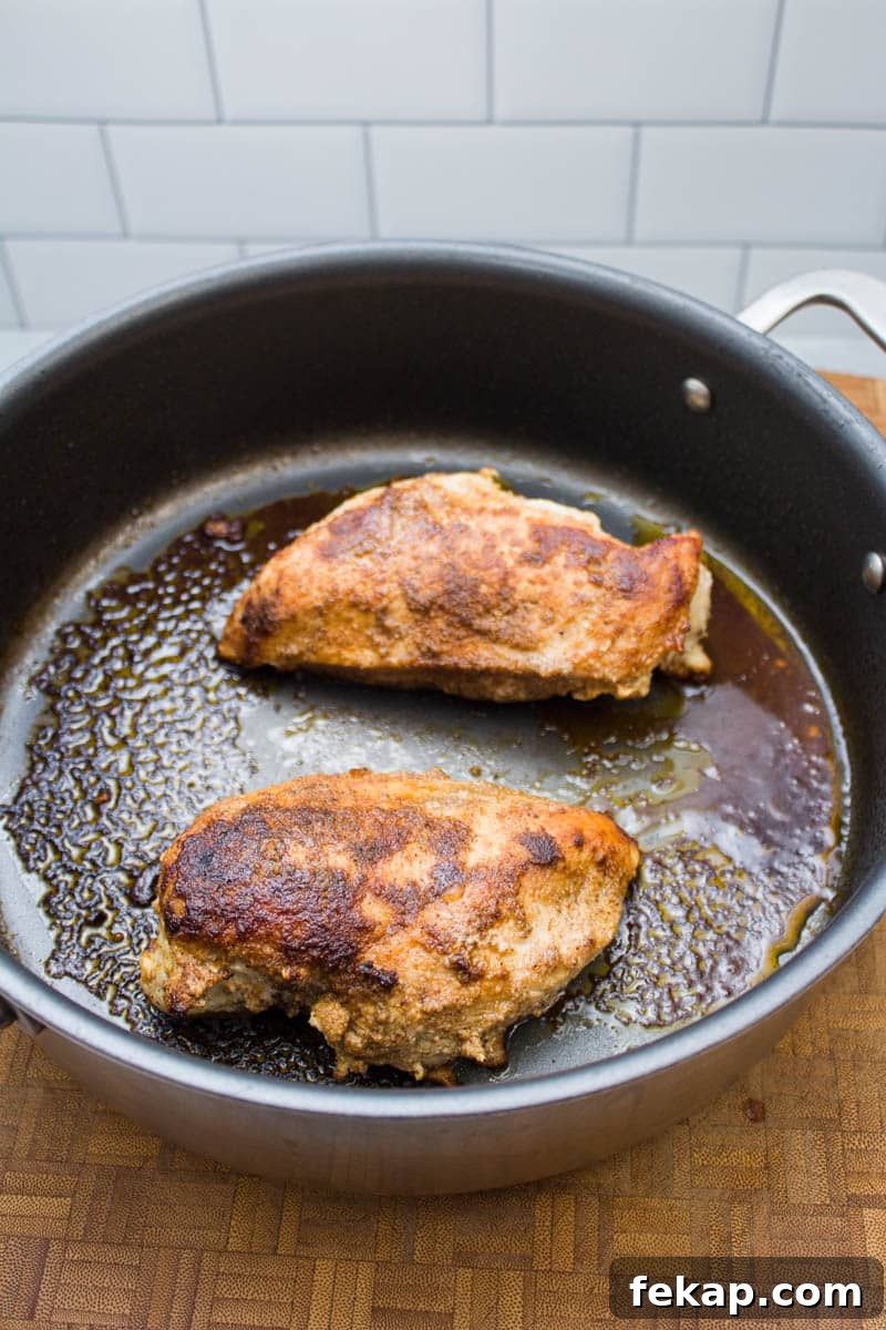 Chicken breasts cooking in a skillet.