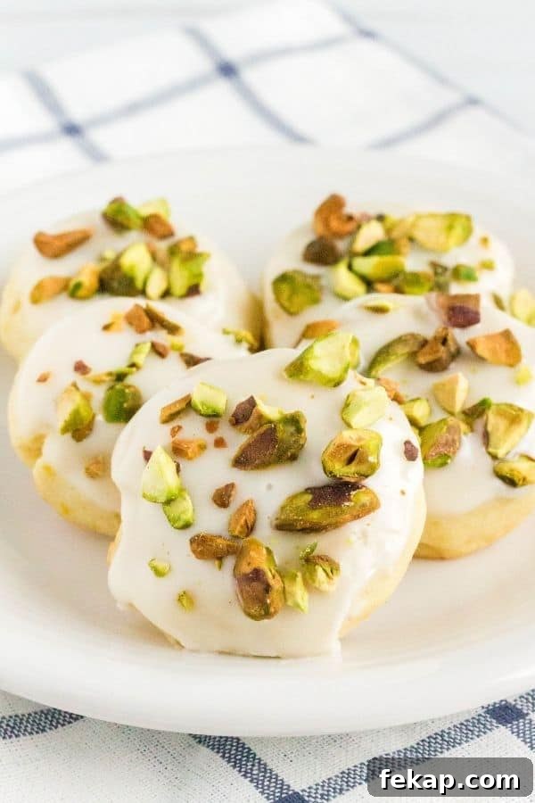 5 lemon pistachio cookies on a white serving plate atop a blue and white checked napkin