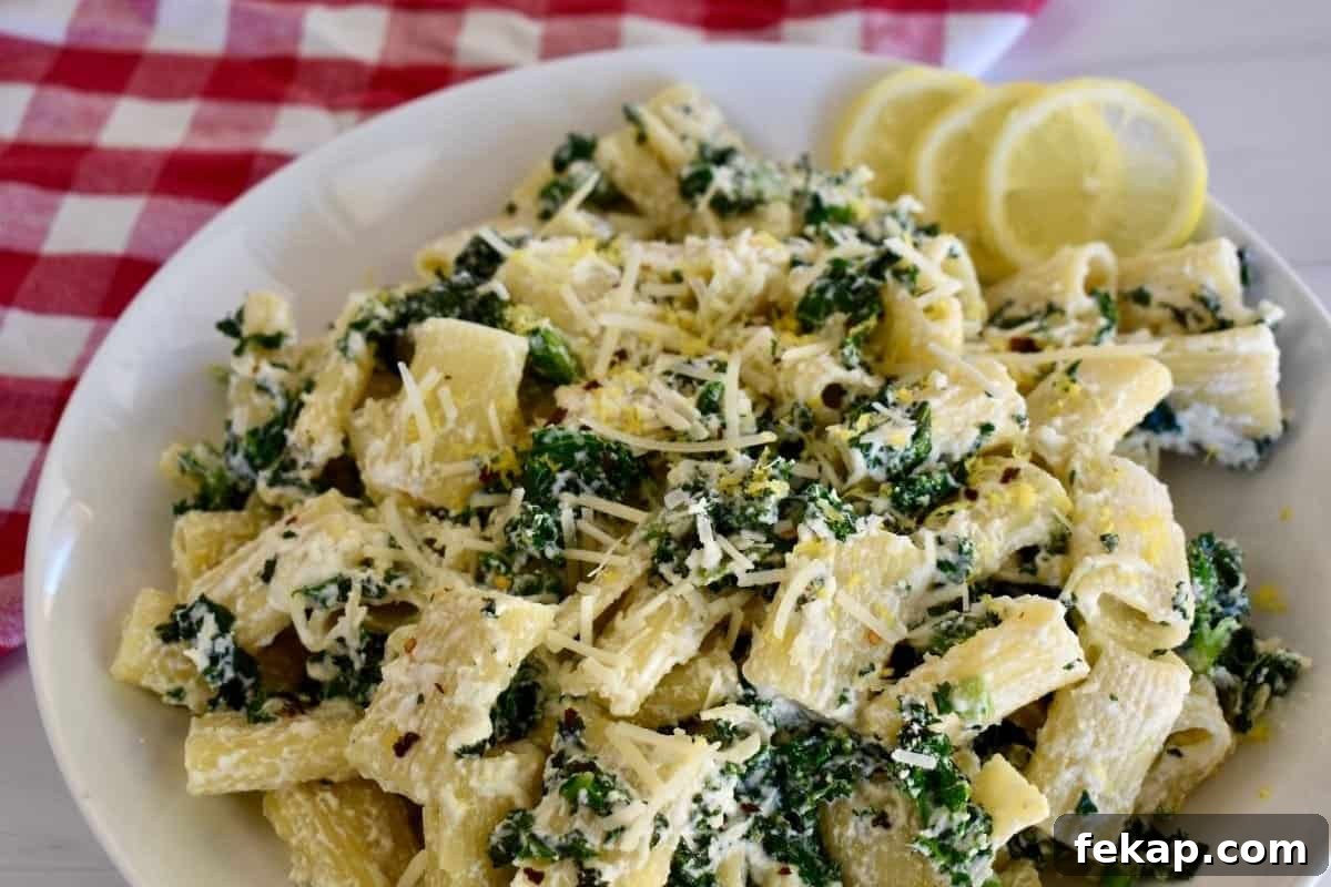 Lemon ricotta pasta served on a white plate with lemon slices nearby.