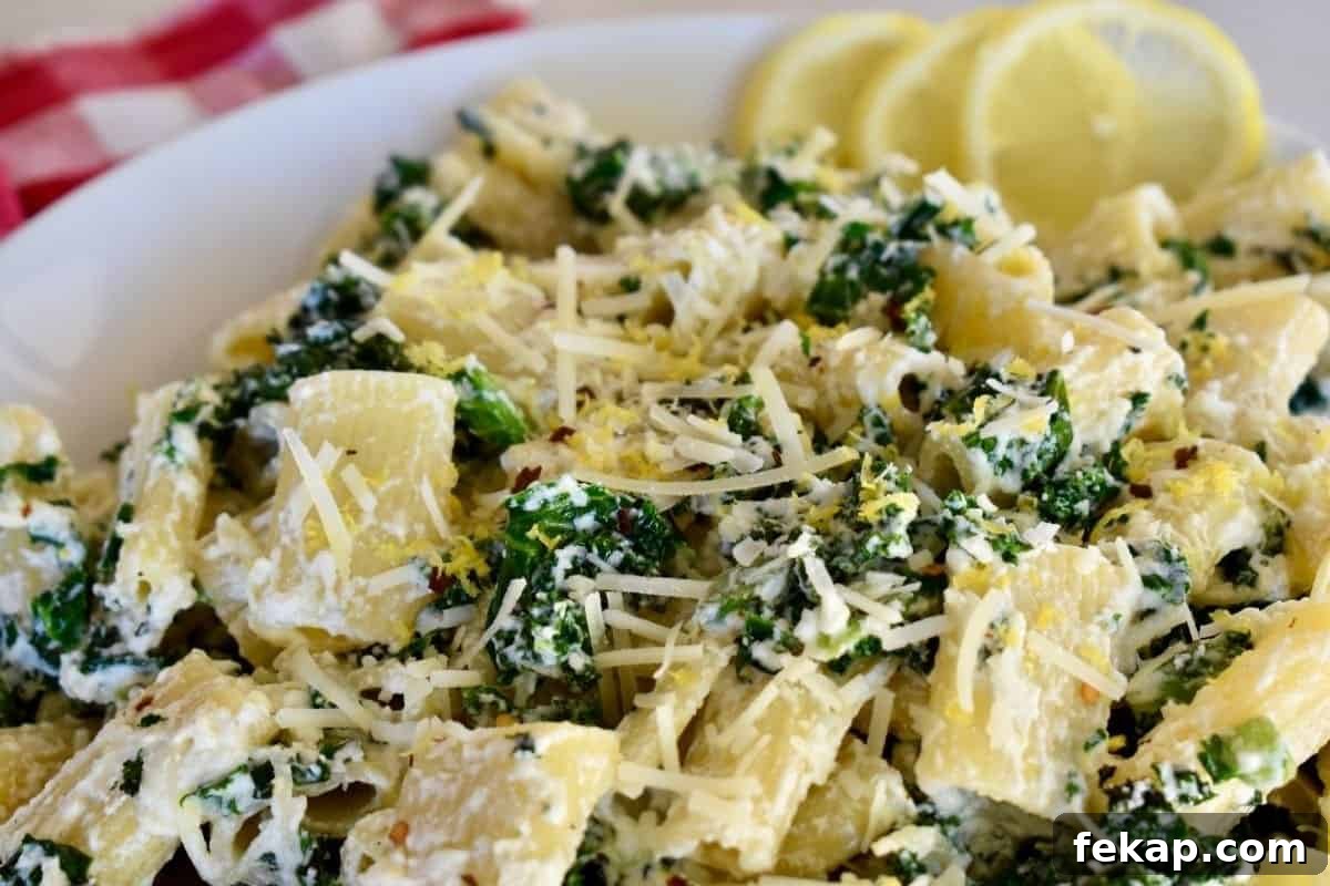 Lemon ricotta pasta in a white serving bowl with lemon slices on the side.