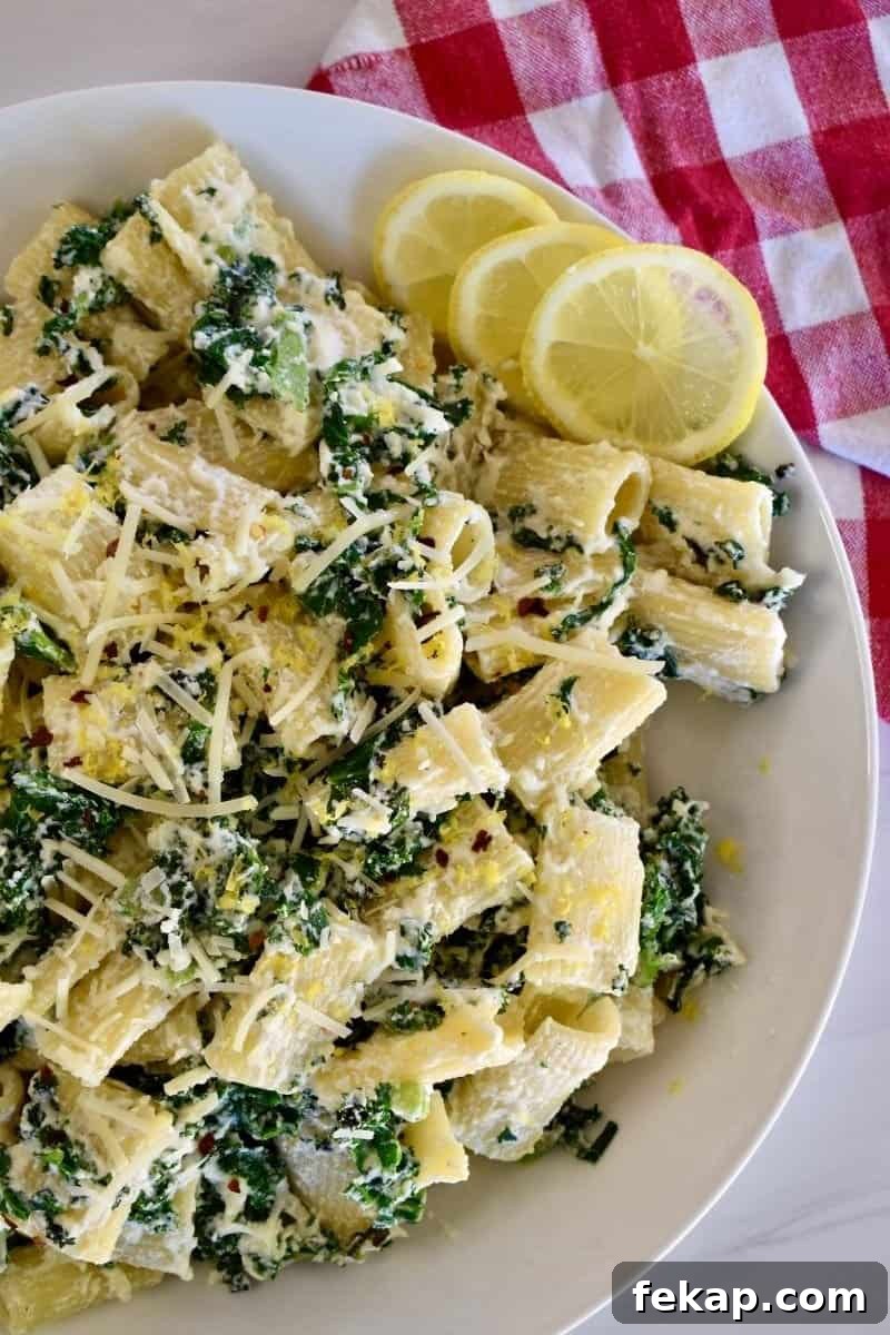 Overhead photo of lemon ricotta pasta in a white bowl with slices of lemon nearby.