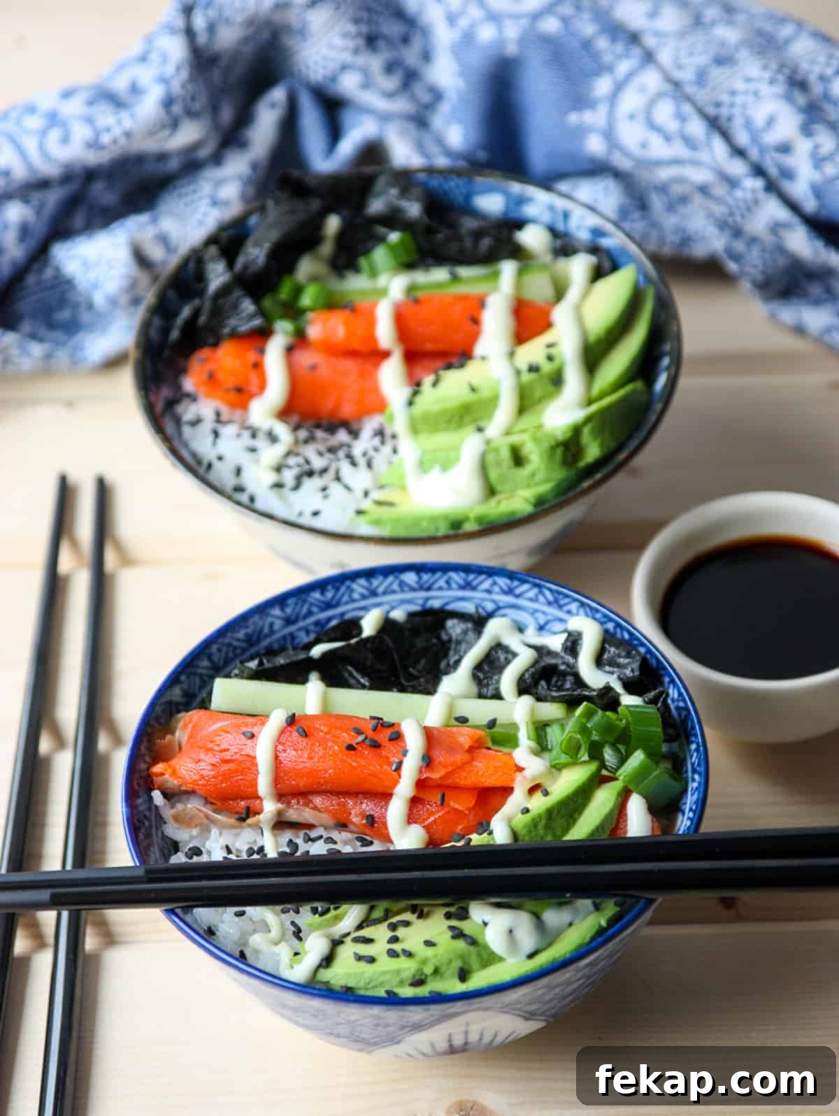 Two salmon sushi bowls with chopsticks.