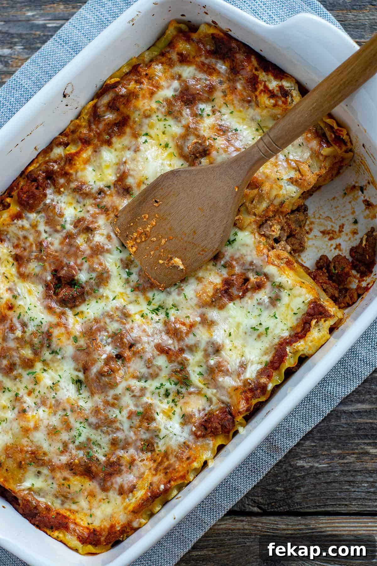 Homestyle Lasagna with Jarred Sauce Recipe 6 baked lasagna in white rectangular dish with slice removed wooden spoon on top