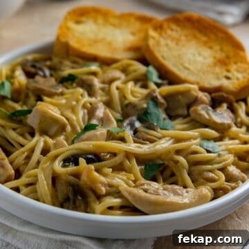 Southern Chicken Tetrazzini in a white bowl with two pieces of toasted buttered bread slices.
