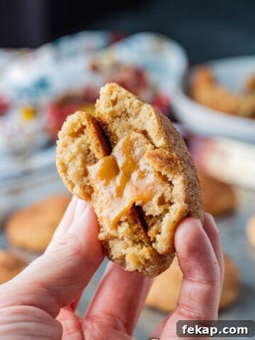 Baked stuffed snickerdoodle broken in half in hand.