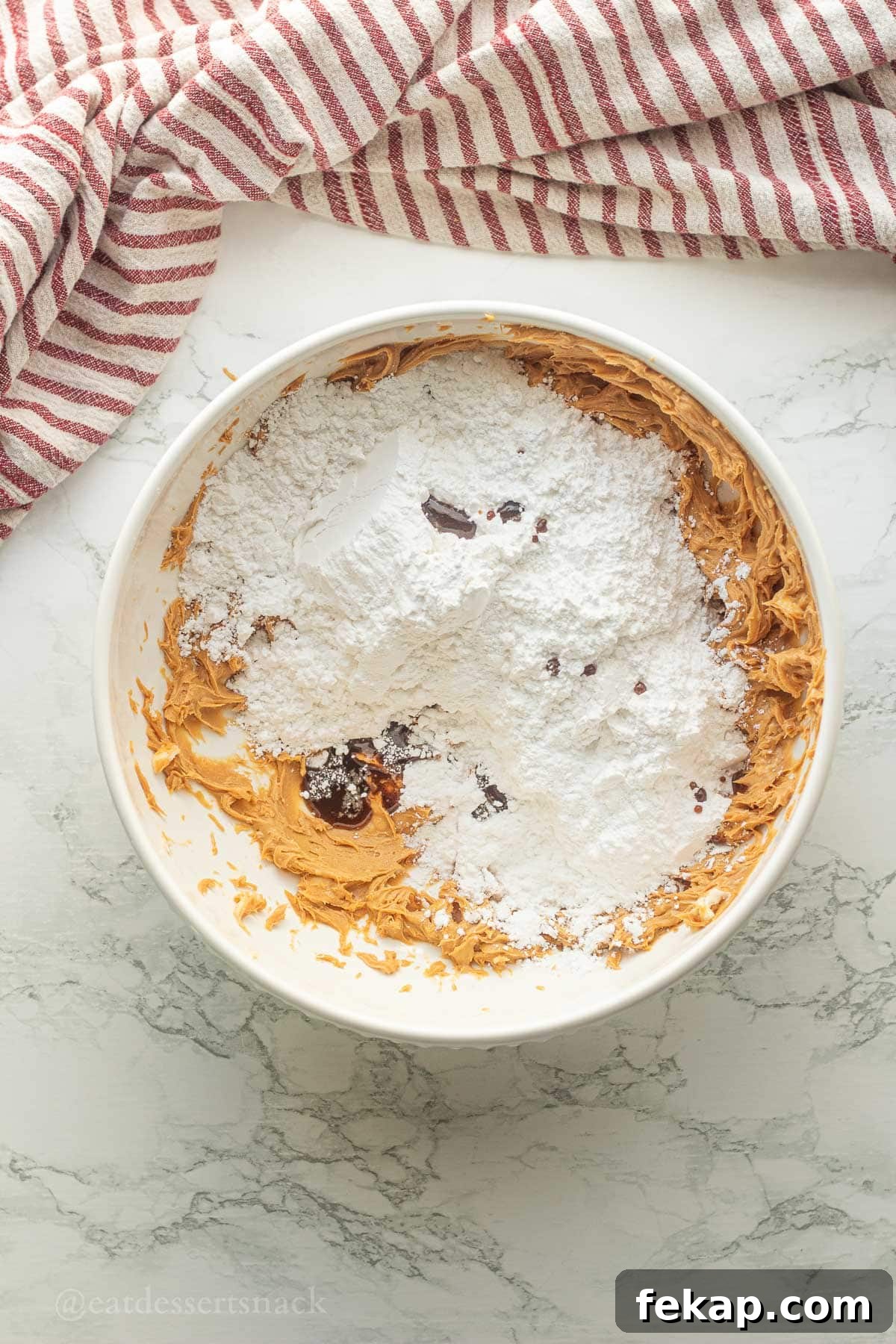 Powdered sugar and vanilla in bowl of peanut butter.