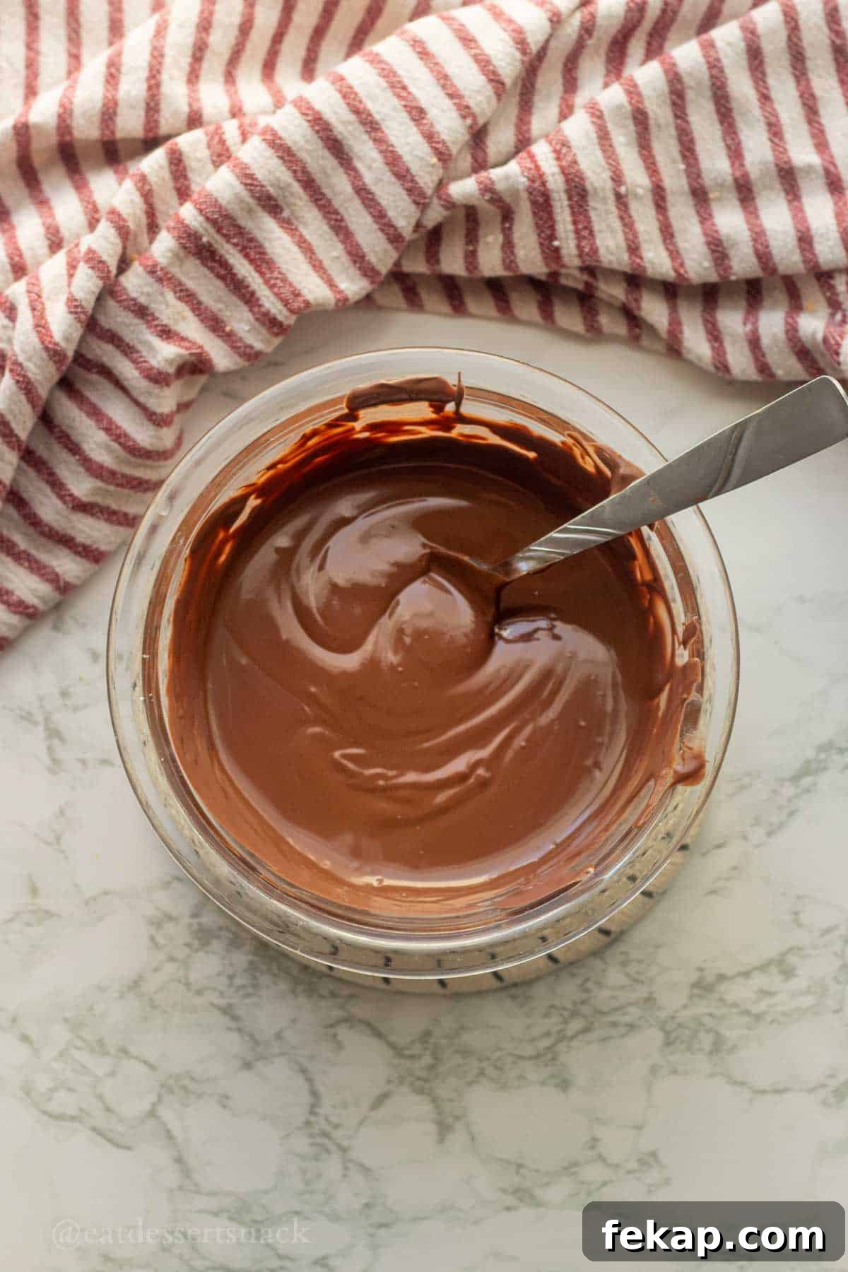 Melted chocolate in bowl with spoon.