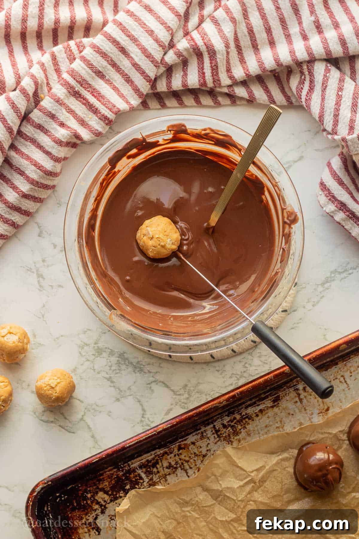 Dipping peanut butter balls into bowl of melted chocolate.