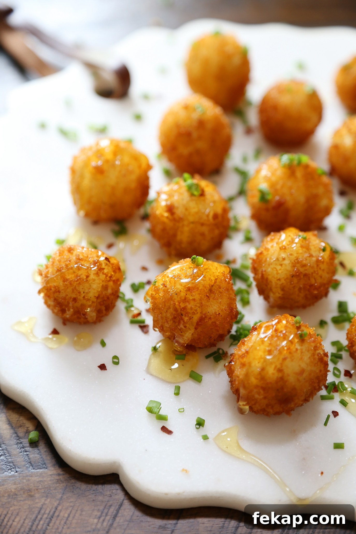 Crispy Goat Cheese Poppers with Honey Drizzle 5 Crispy goat cheese poppers on a platter with honey and chives