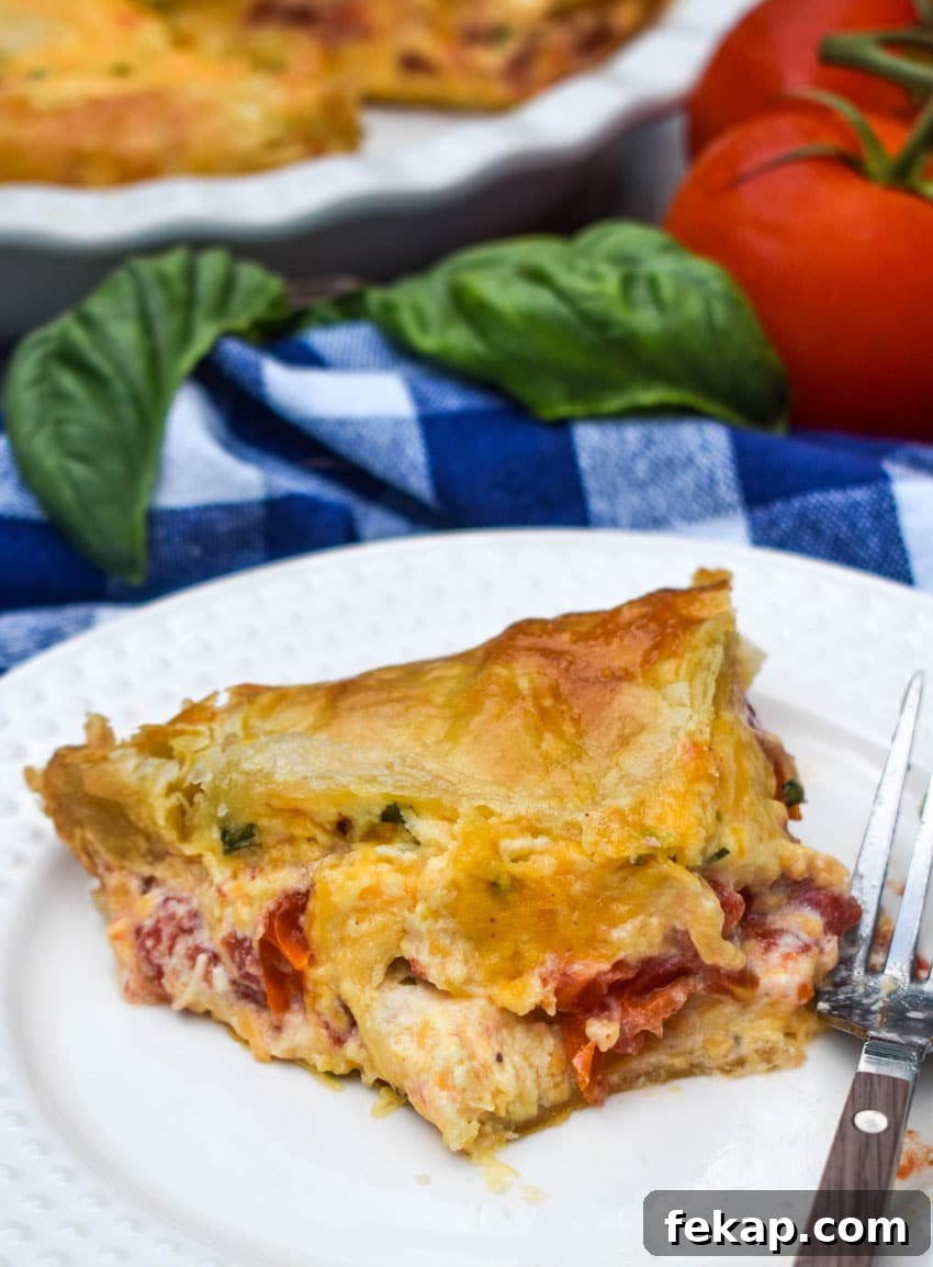 Savory Tomato Pie with Flaky Puff Pastry Crust 8 a slice of tomato pie with puff pastry crust on a small white plate with a fork resting on the side