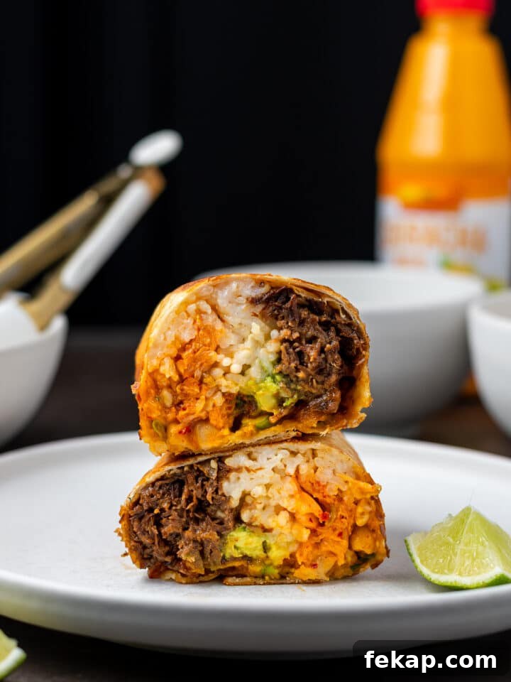 Korean BBQ Shredded Beef Burritos Recipe 10 two halves of burrito stacked on top of each other on a white plate with a lime wedge