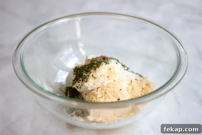 a bowl with cream cheese,sour cream, parmesan cheese and parsley.