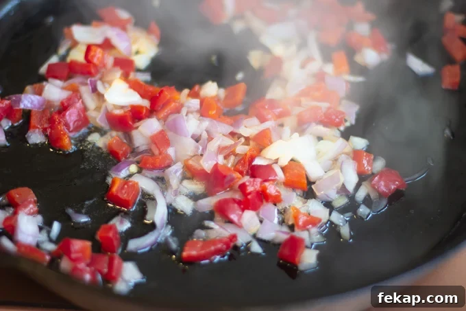 sauteed onions, red bell peppers in skillet cooking