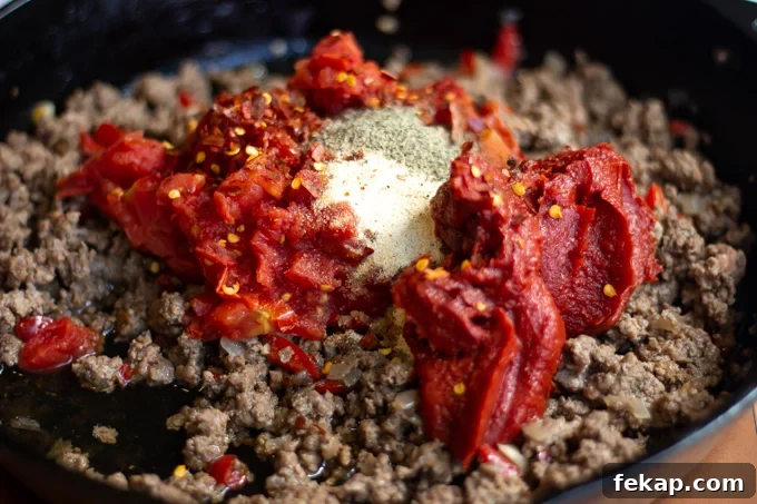 Meat sauce ingredient going into the skillet with the ground beef