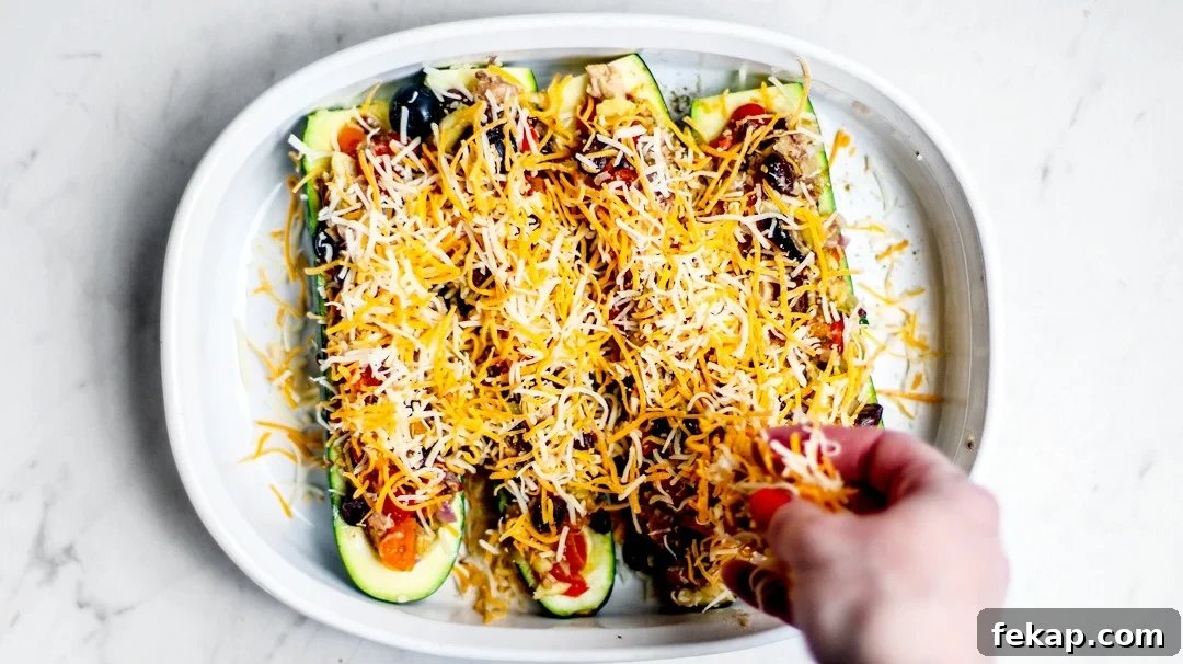 Tex-Mex Zucchini Boats Stuffed with King Oscar Sardines 4 Stuffed zucchini boats being sprinkled with cheese.