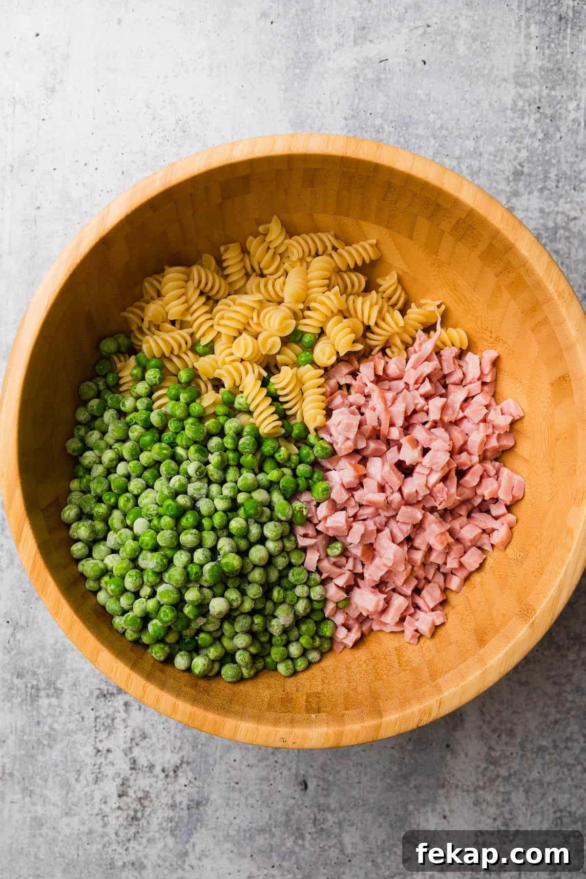 Copycat Ruby Tuesday Ham and Pea Pasta Salad Recipe 5 Adding salad ingredients to a bowl.