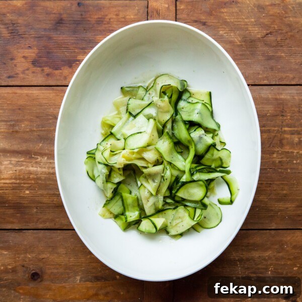 7 Delicious Ways to Cook Zucchini: Roast, Saute, Grill 6 White serving plate of Zucchini Ribbon Salad on a wooden table.