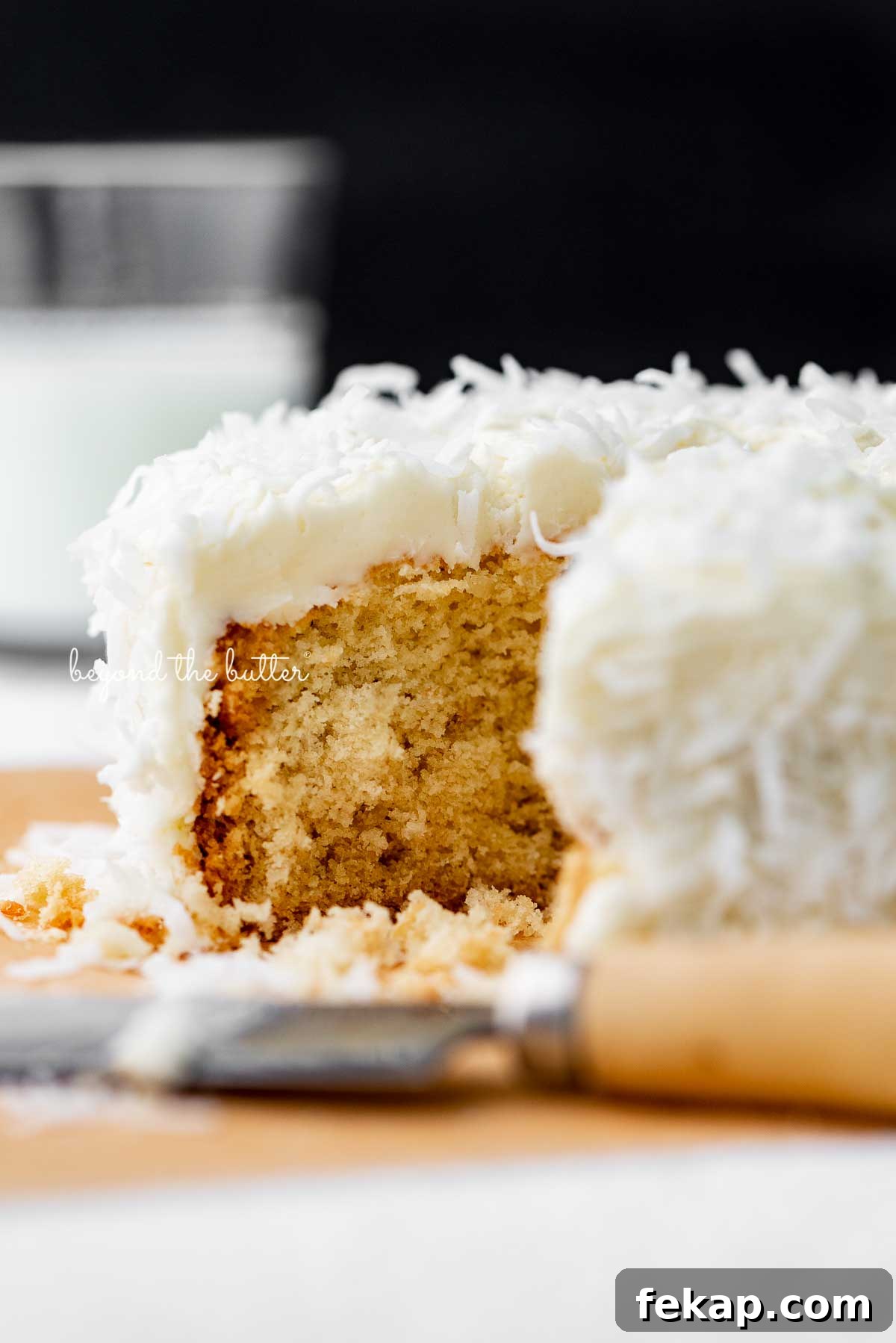 Moist Single Layer Coconut Cake Recipe 6 Sliced single layer coconut cake with black background | © Beyond the Butter®