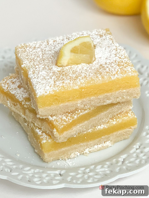 Lemon bars served on a plate, dusted with powdered sugar