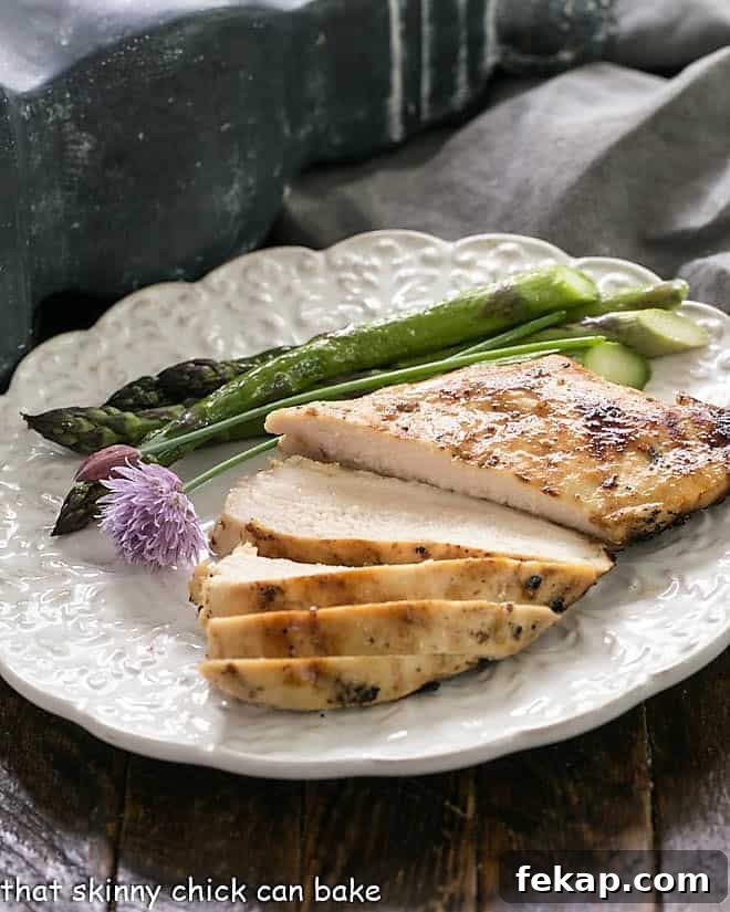 Mustard, Garlic, Lime Marinated Chicken Breasts is flavored with the BEST chicken marinade! A sliced chicken breast on a white dinner plate with asparagus.