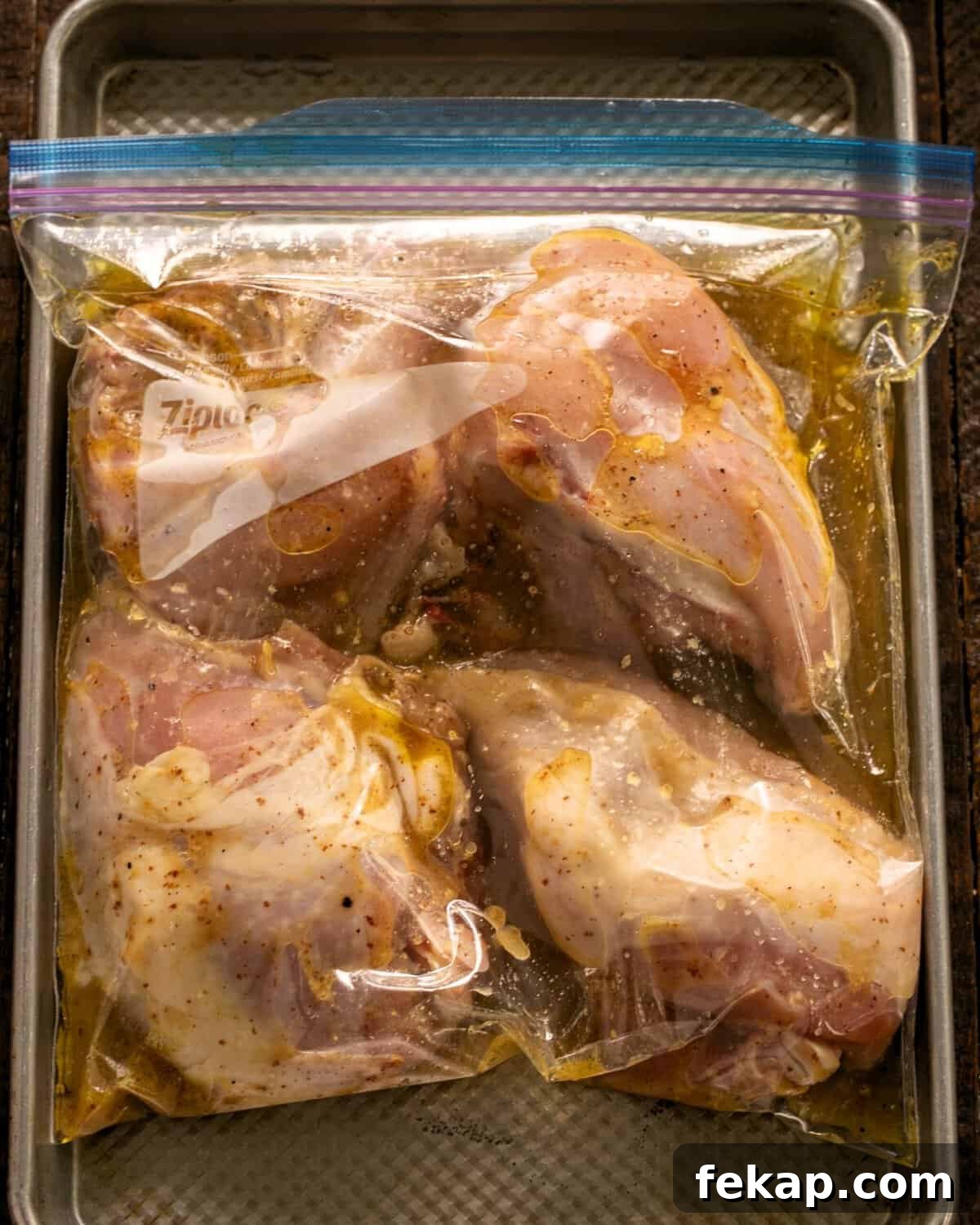 Zesty Mustard, Garlic and Lime Marinated Chicken Breasts 4 Chicken with marinade in a Ziploc bag on a sheetpan.