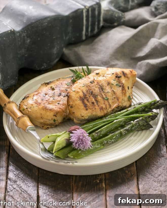 Zesty Mustard, Garlic and Lime Marinated Chicken Breasts 5 2 chicken breasts on a dinner plate with asparagus spears and a bamboo handle fork.