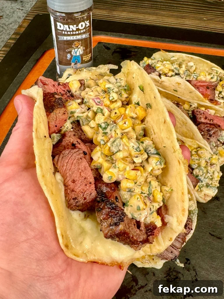 Grilled Steak Tacos with Elote Style Corn Recipe 5 holding an elote steak tacos