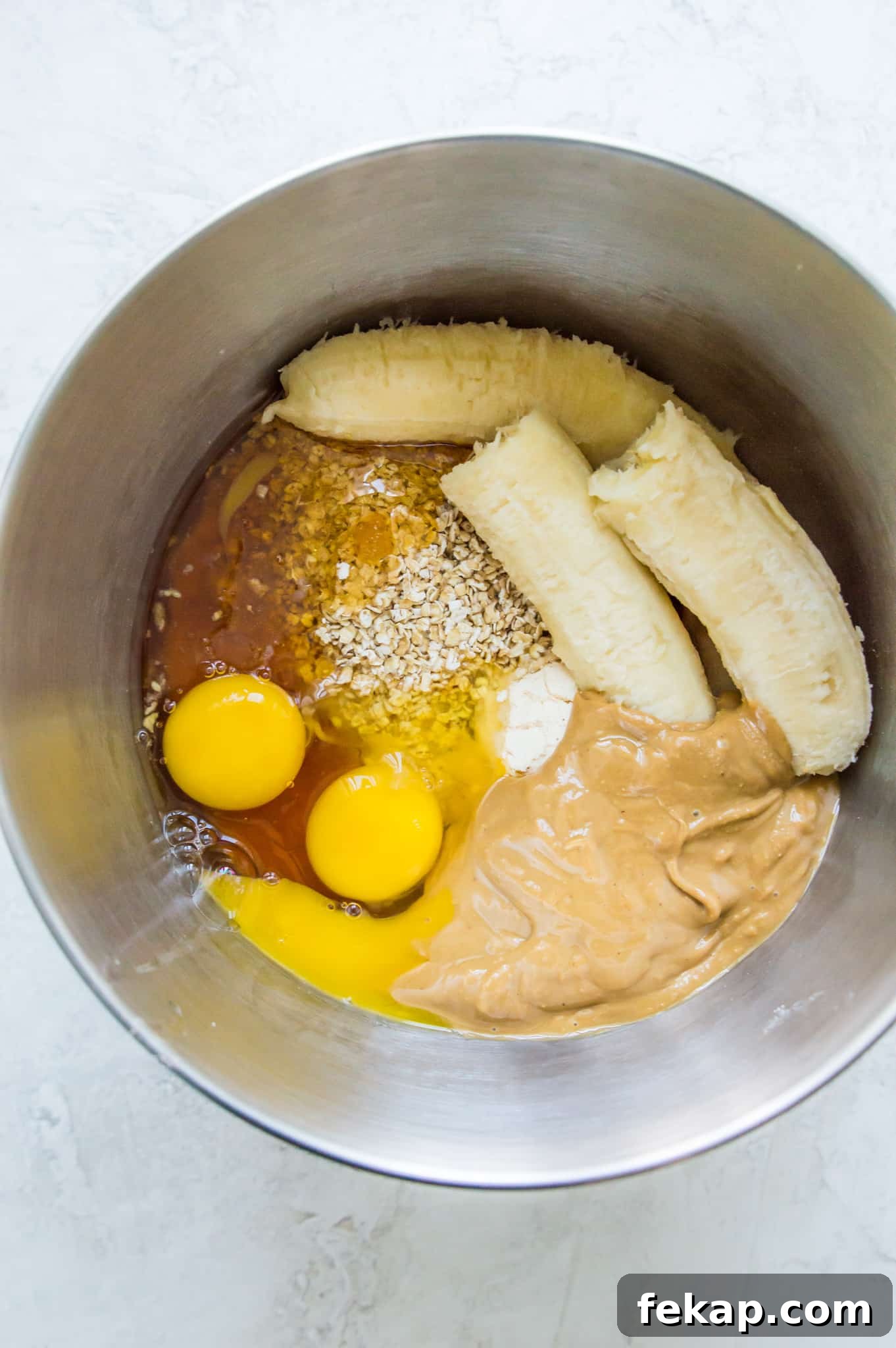 Banana Protein Muffins: 12g Protein Per Muffin 3 A mixing bowl with ripe bananas, peanut butter, eggs, oats and flour in it.