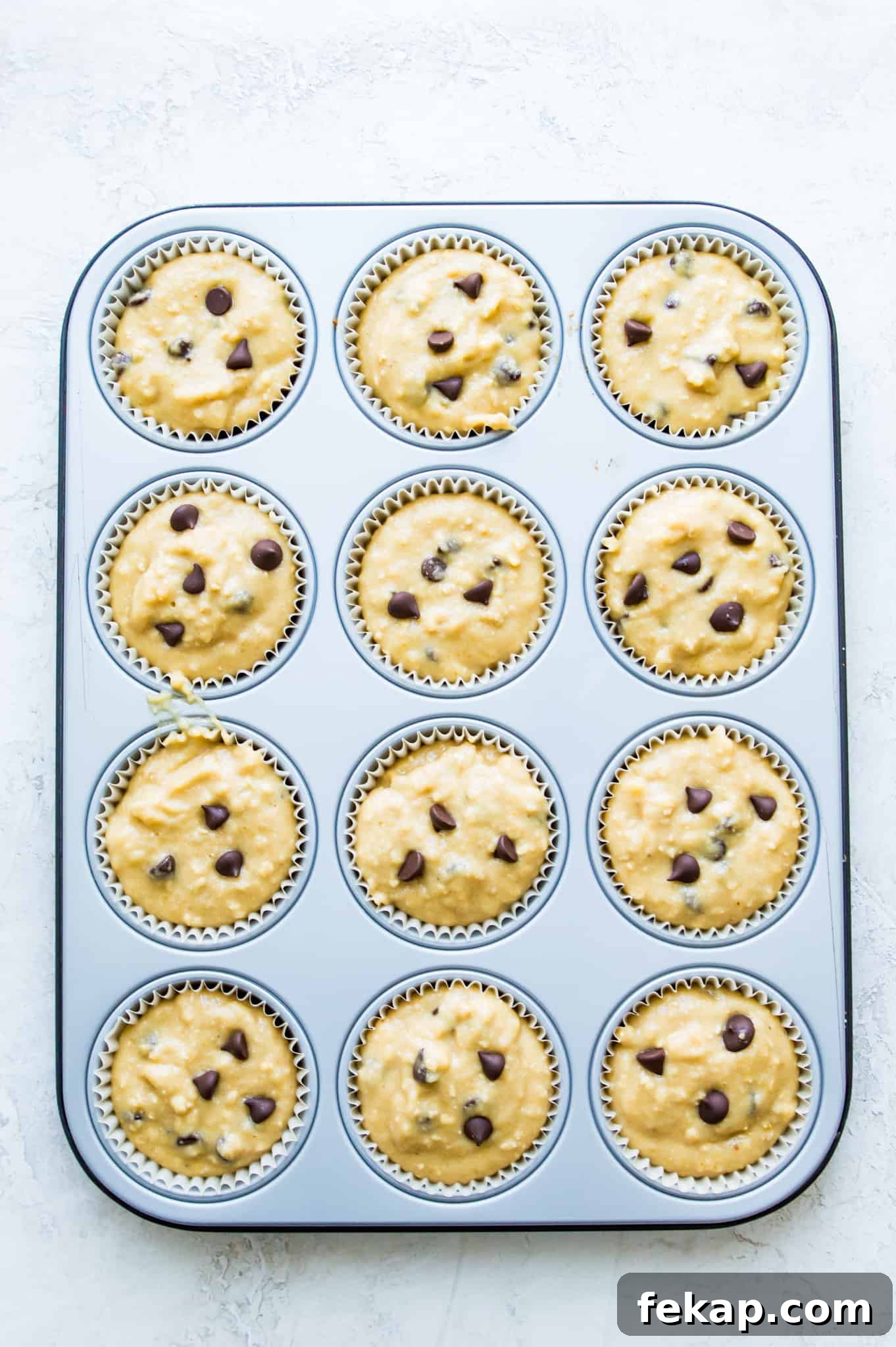 Banana Protein Muffins: 12g Protein Per Muffin 4 A muffin pan with chocolate chip muffin batter in it.