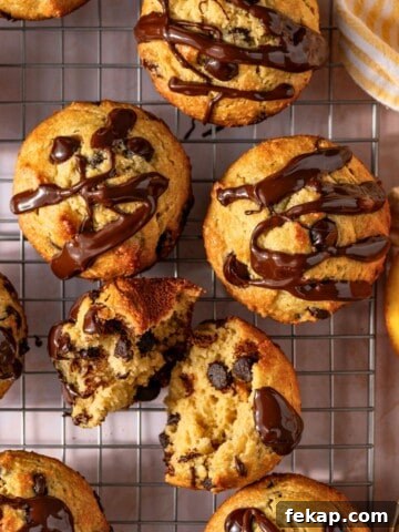 Banana Protein Muffins: 12g Protein Per Muffin 7 A batch of chocolate chip muffins drizzled in melted chocolate on a wire baking rack.