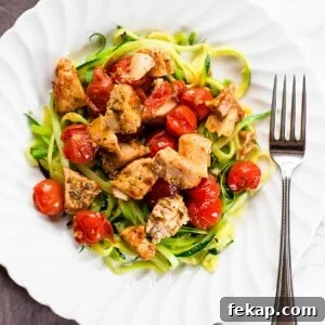 Zoodles with tomatoes and chicken on a white plate.