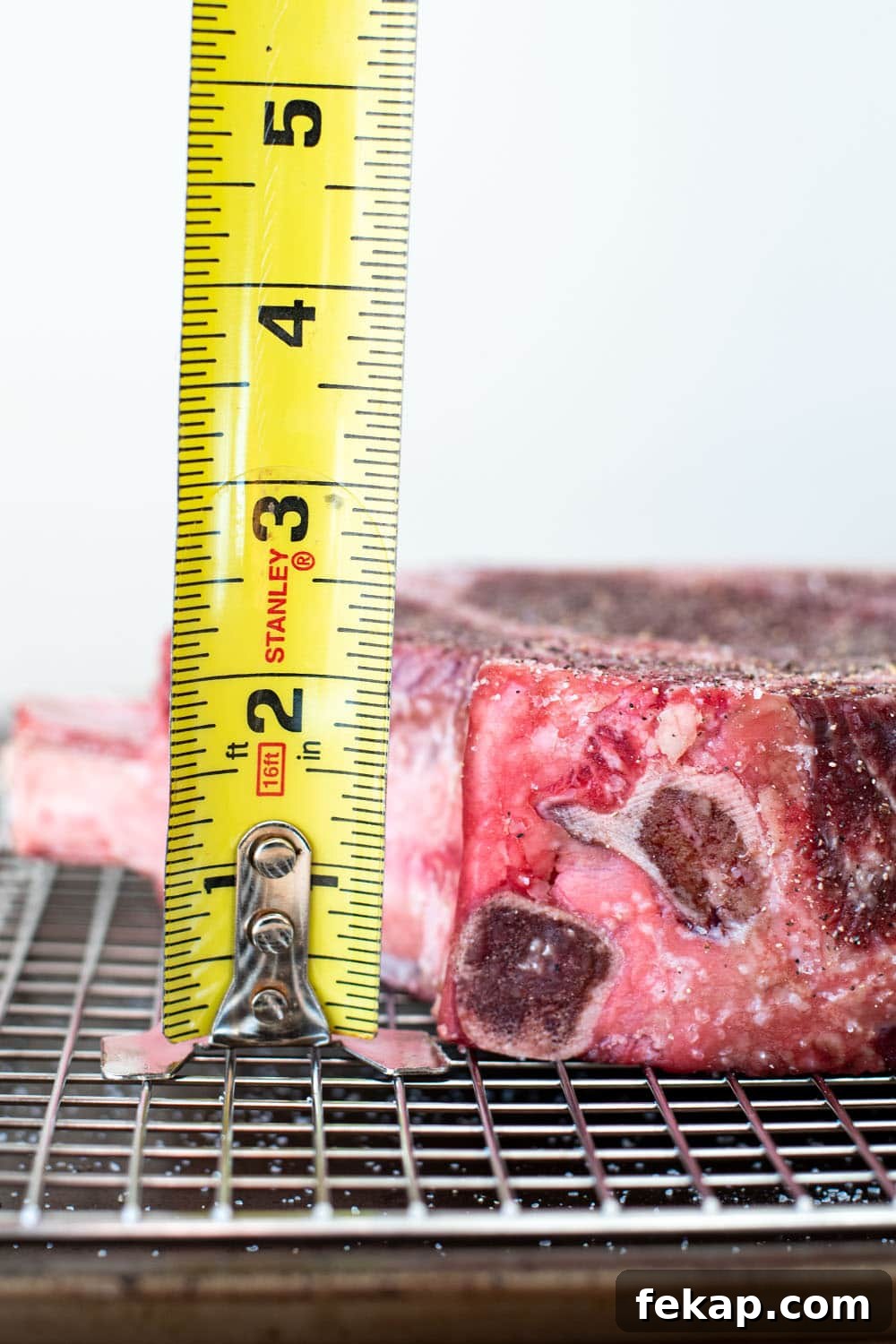 Reverse Sear Steak: Perfect Crust and Juicy Center 3 2 inch thick uncooked cowboy steak being measured with a tape measure.