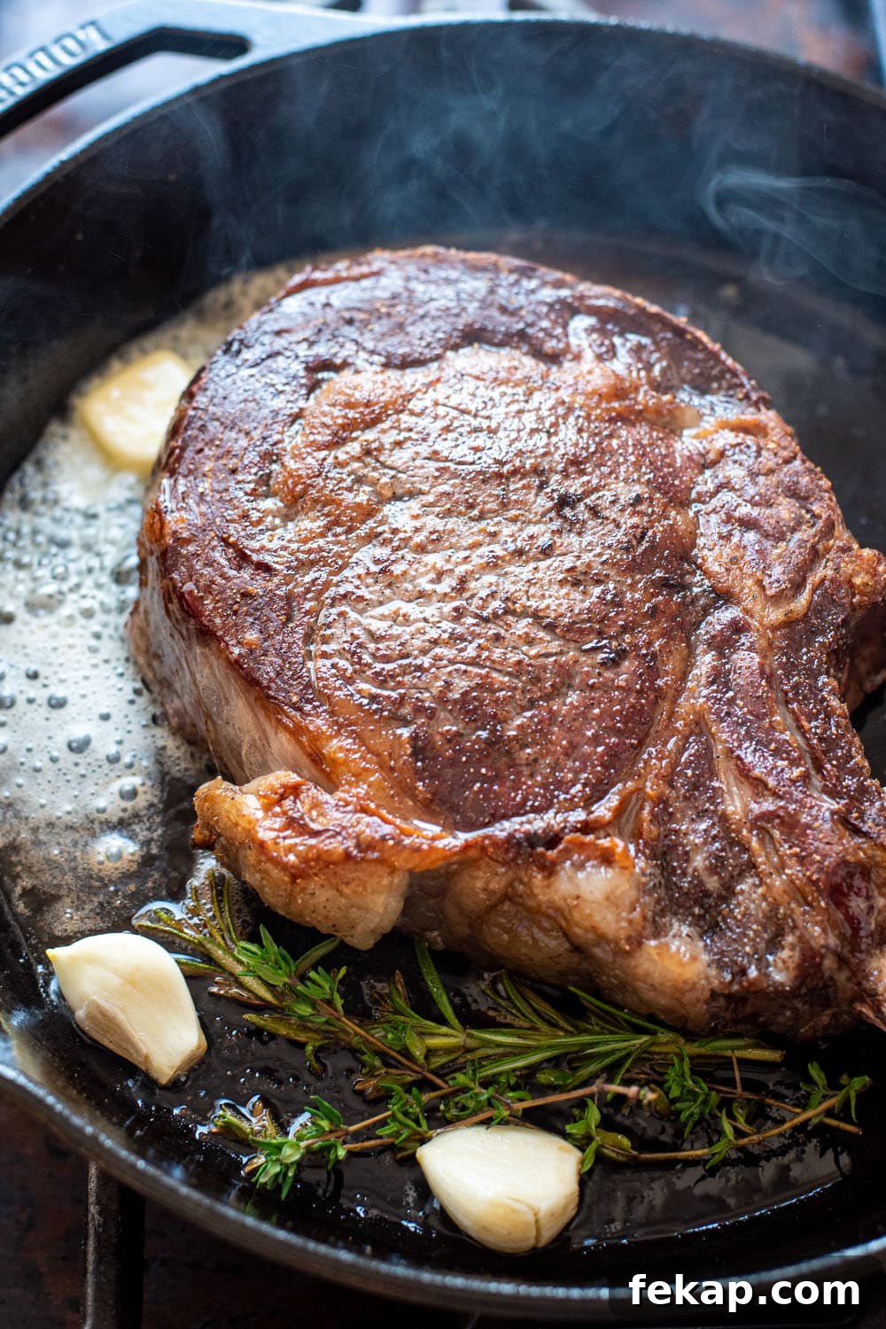 Reverse Sear Steak: Perfect Crust and Juicy Center 6 Searing a cowboy steak in a cast iron skillet with garlic and fresh herbs.